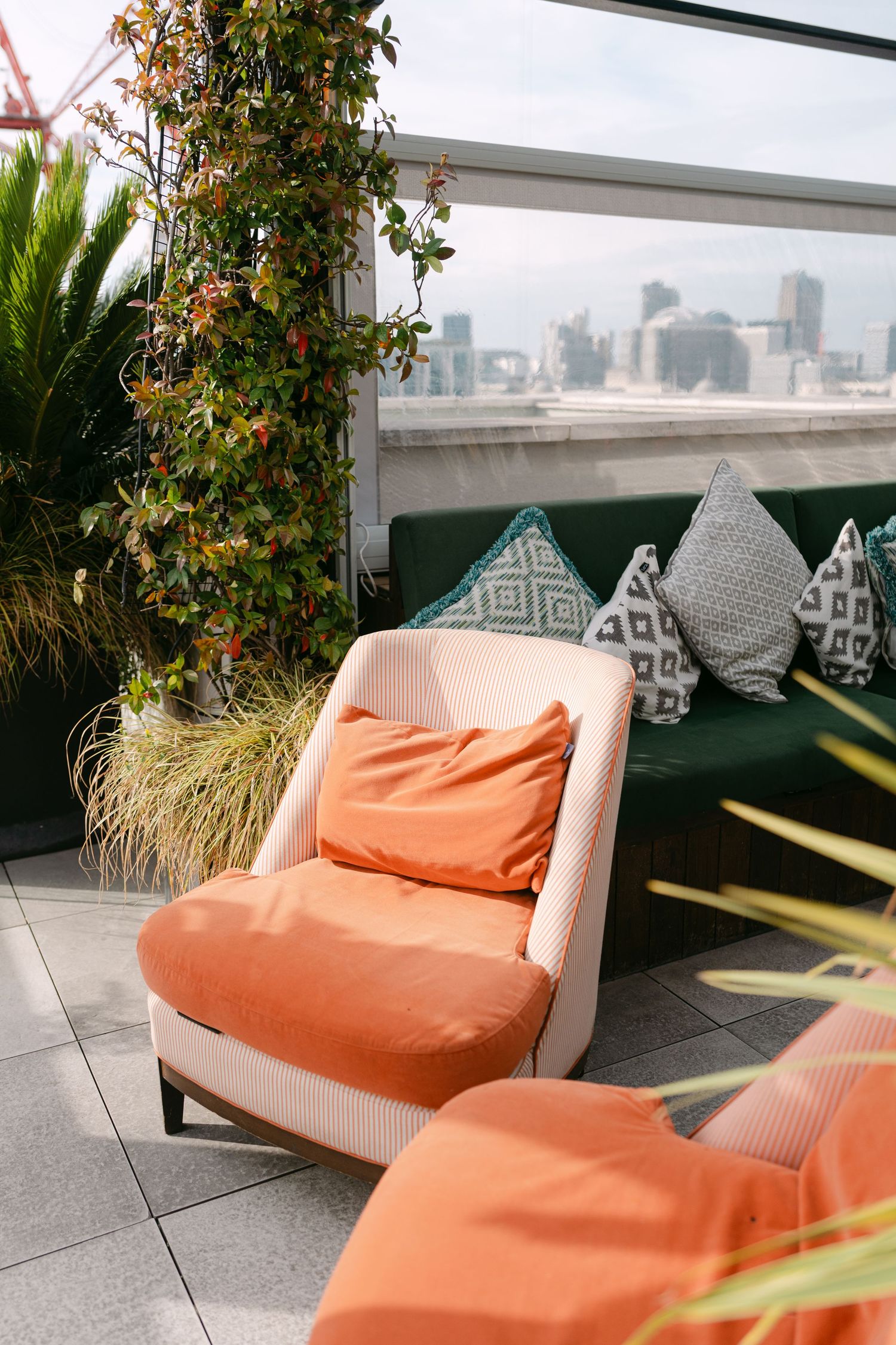 Modern outdoor seating area with orange cushions and geometric pillows on a rooftop terrace.