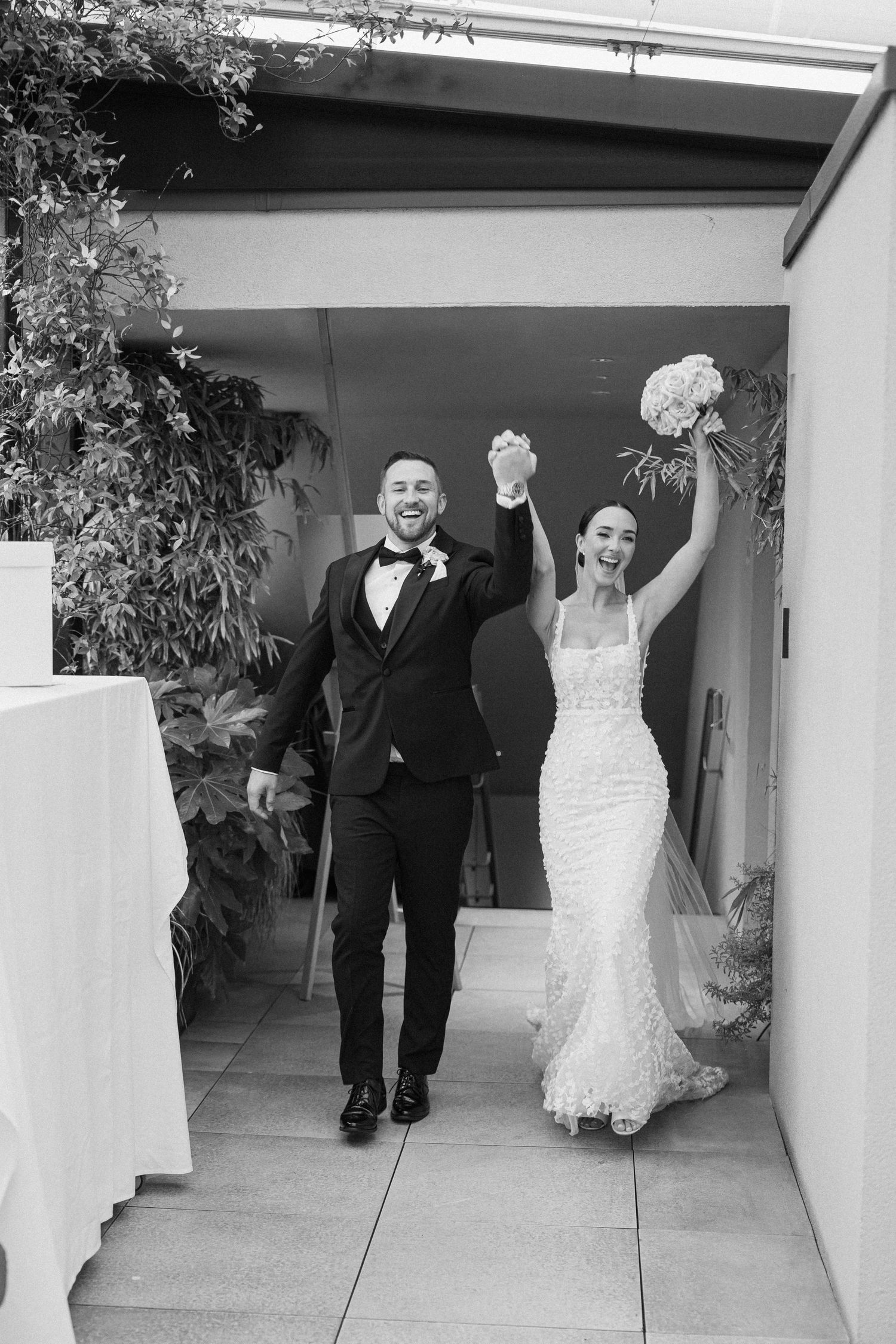 Sequence showing wedding couple joyfully running through a white corridor with plants overhead.