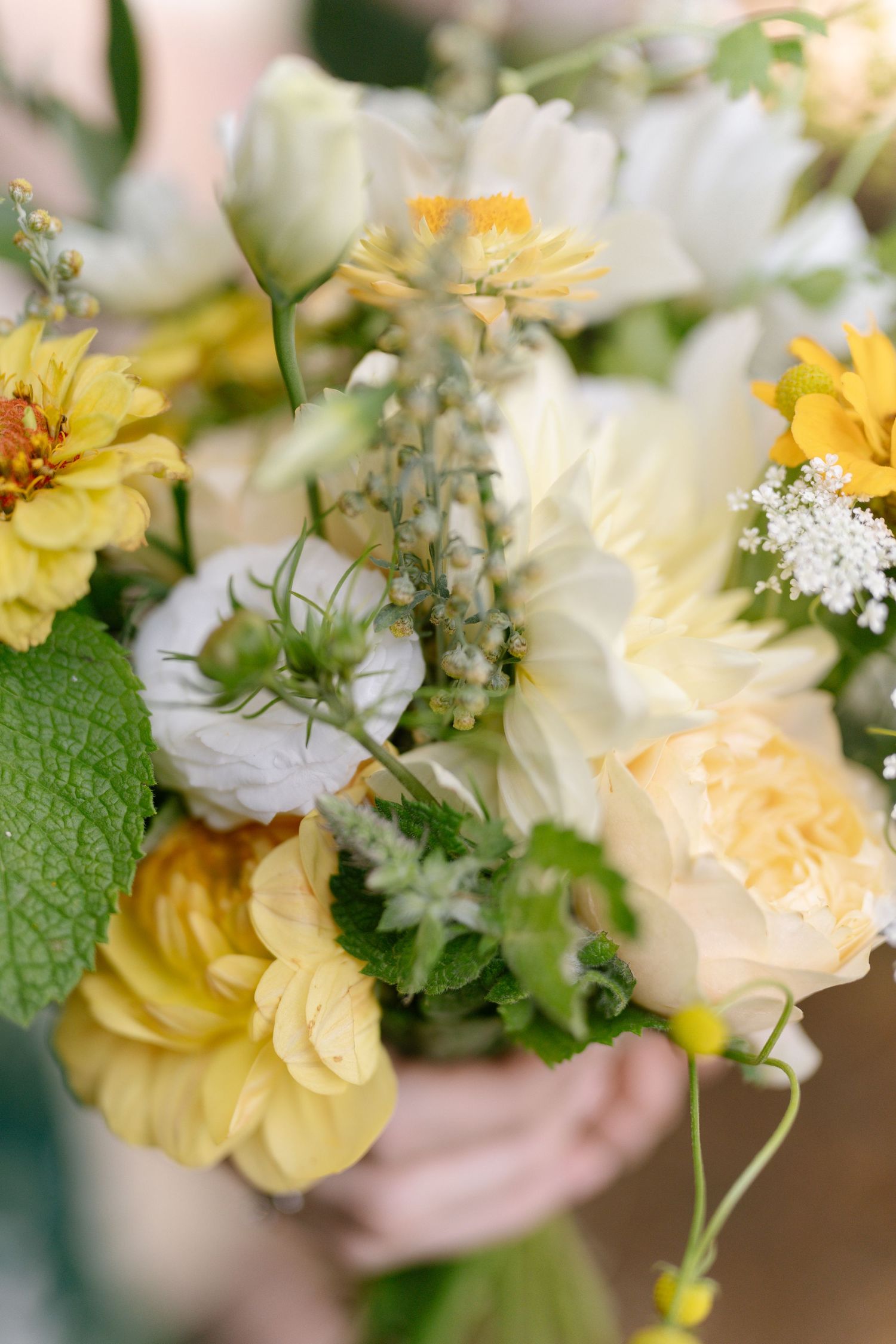 Delicate bouquet of white and yellow garden flowers with greenery.