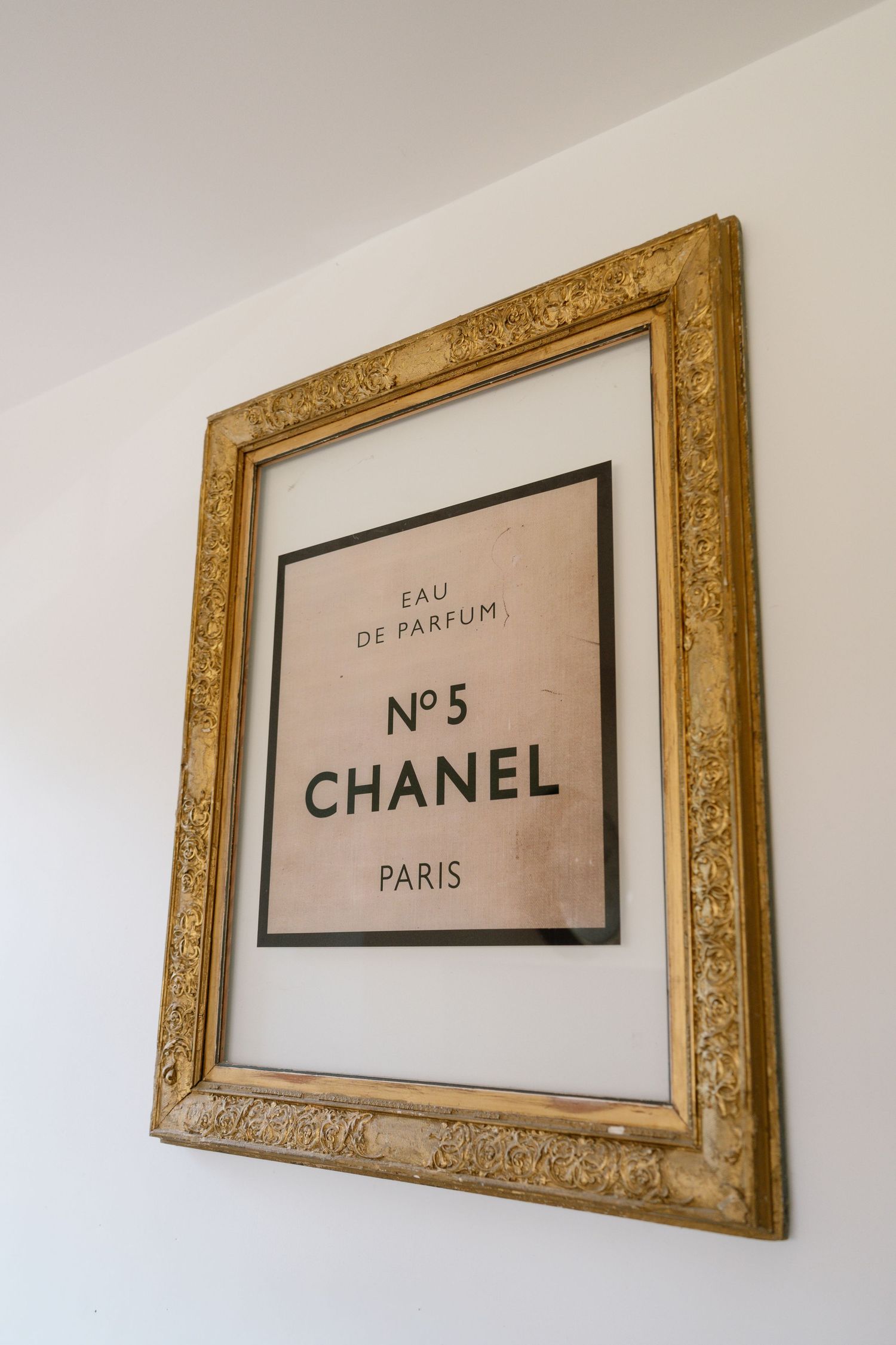 Series of gold-framed Chanel perfume advertisements mounted on a white wall.