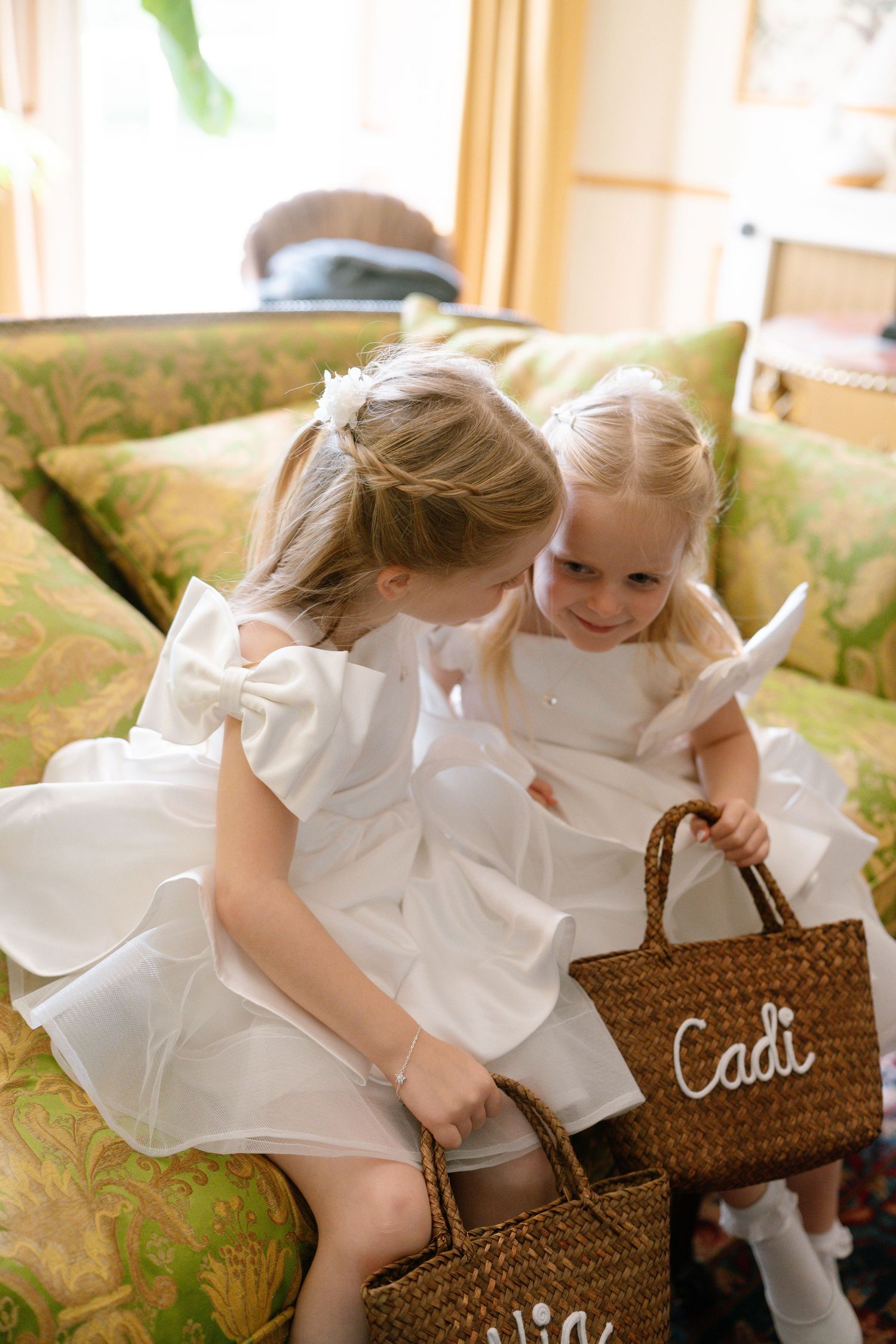 Young attendants in white dresses examine personalized wicker baskets.