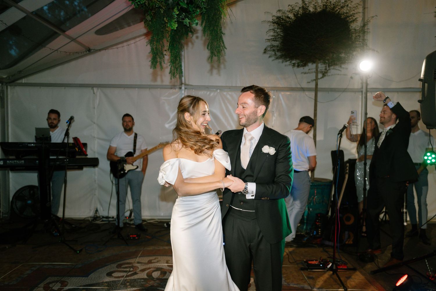A couple dances together at their wedding reception with the band performing behind them.