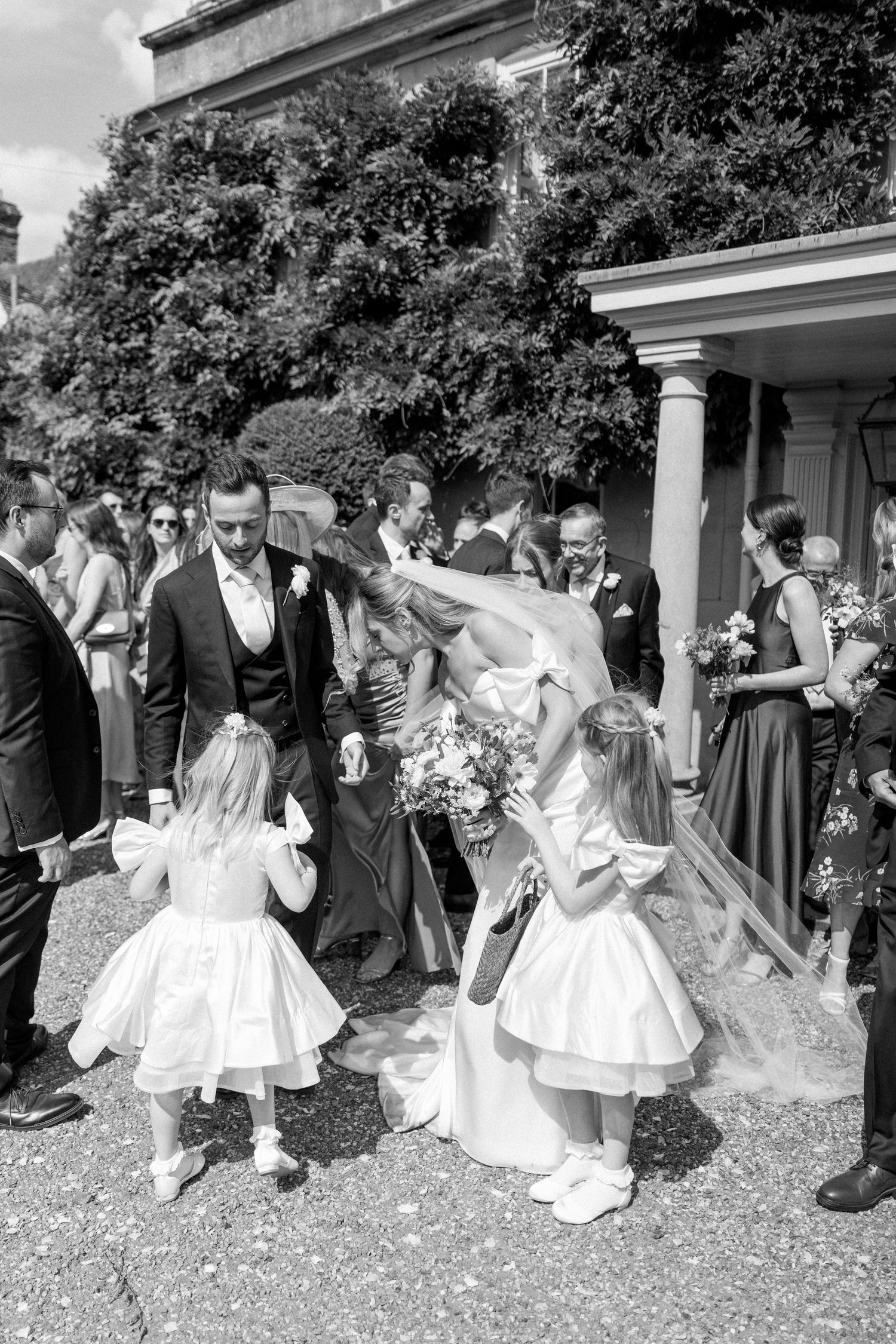 Black and white photo of wedding guests throwing confetti during outdoor celebrations.