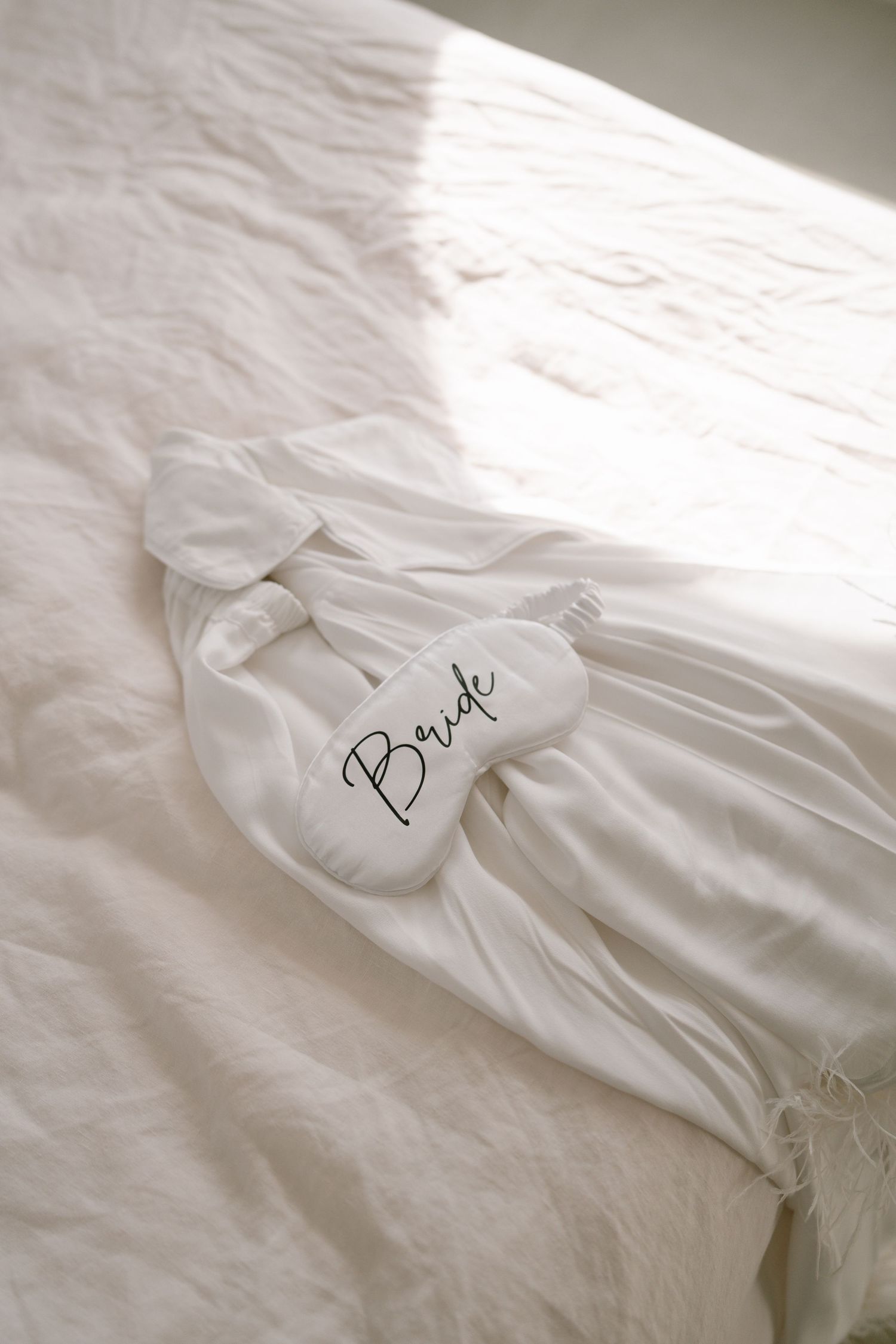 White robes with embroidered text laid out on a light colored bed.