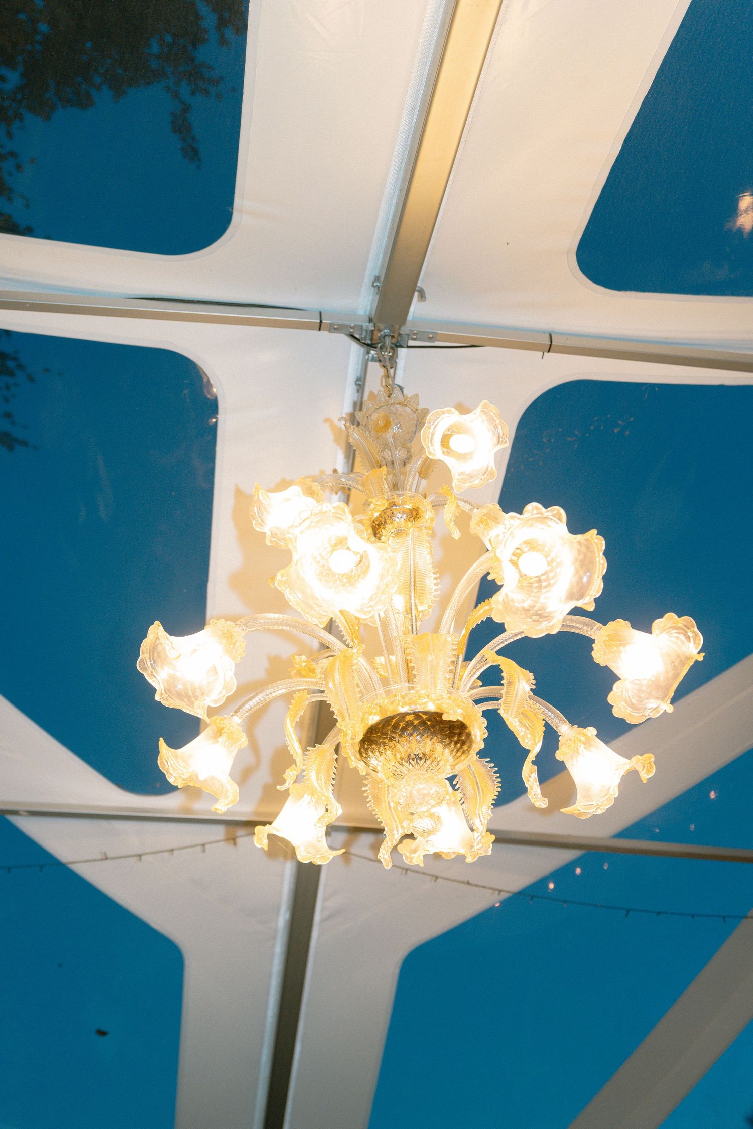 Elegant crystal chandelier with glowing lights against a blue ceiling.