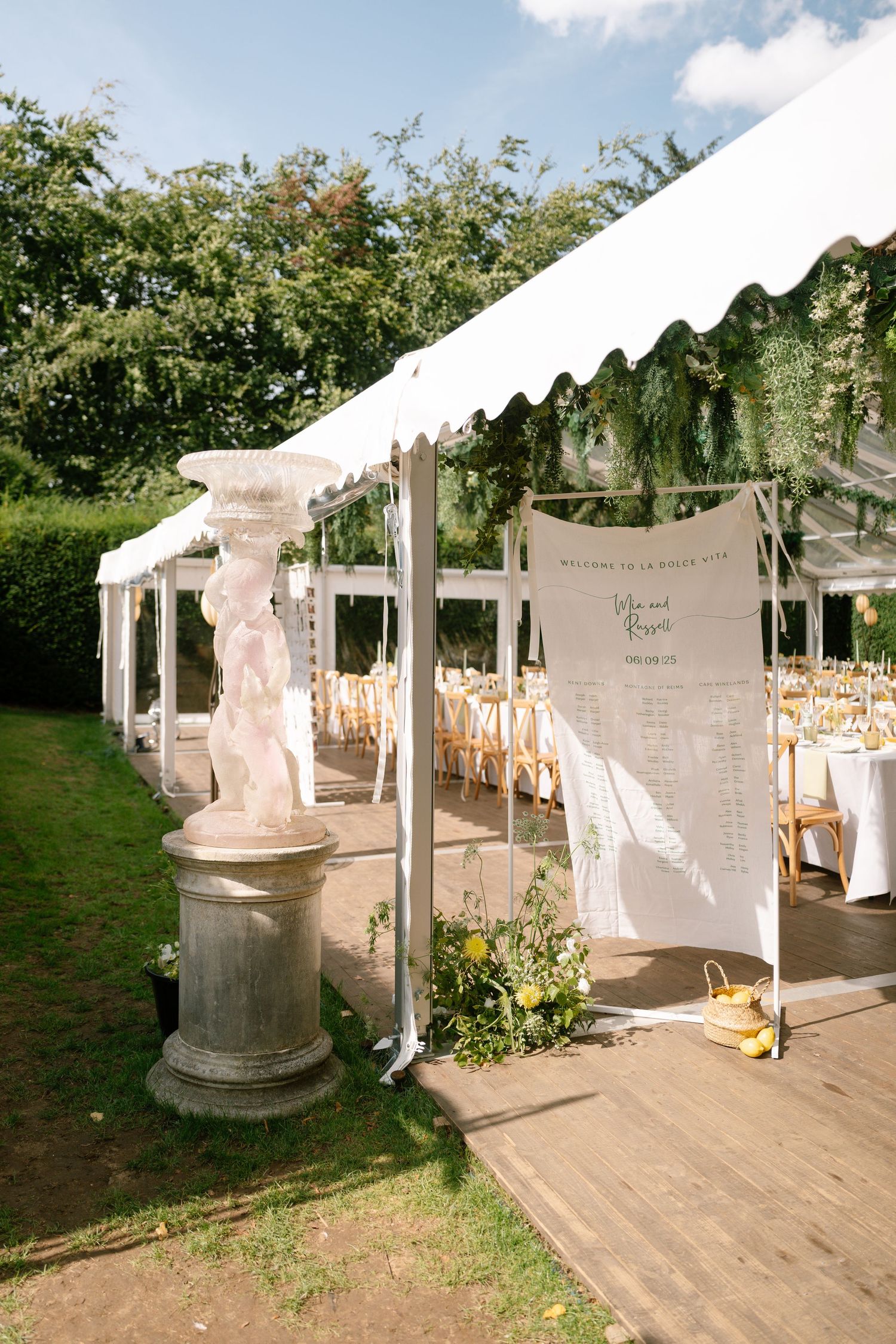 White tent canopies set up outdoors with decorative draping and wooden posts.