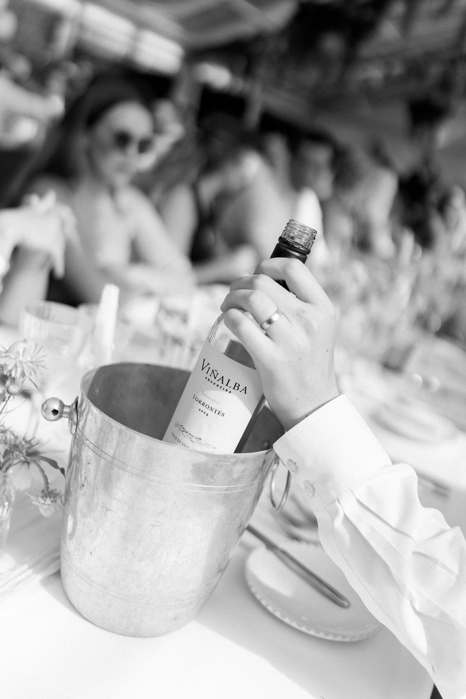 Black and white photo of a wine bottle being pulled from an ice bucket at an elegant event.