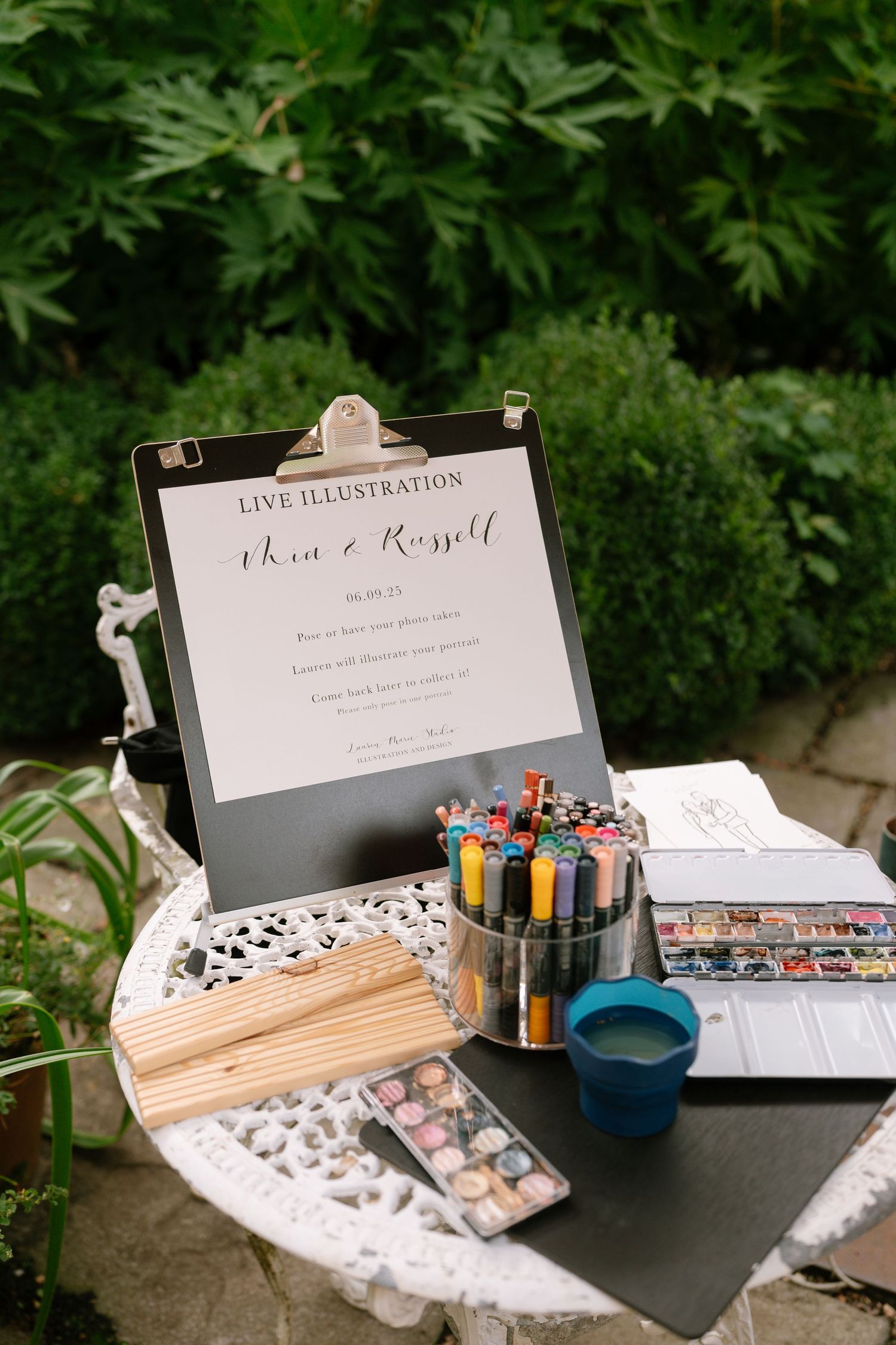 Wedding guest book station with art supplies and illustration materials set up outdoors.