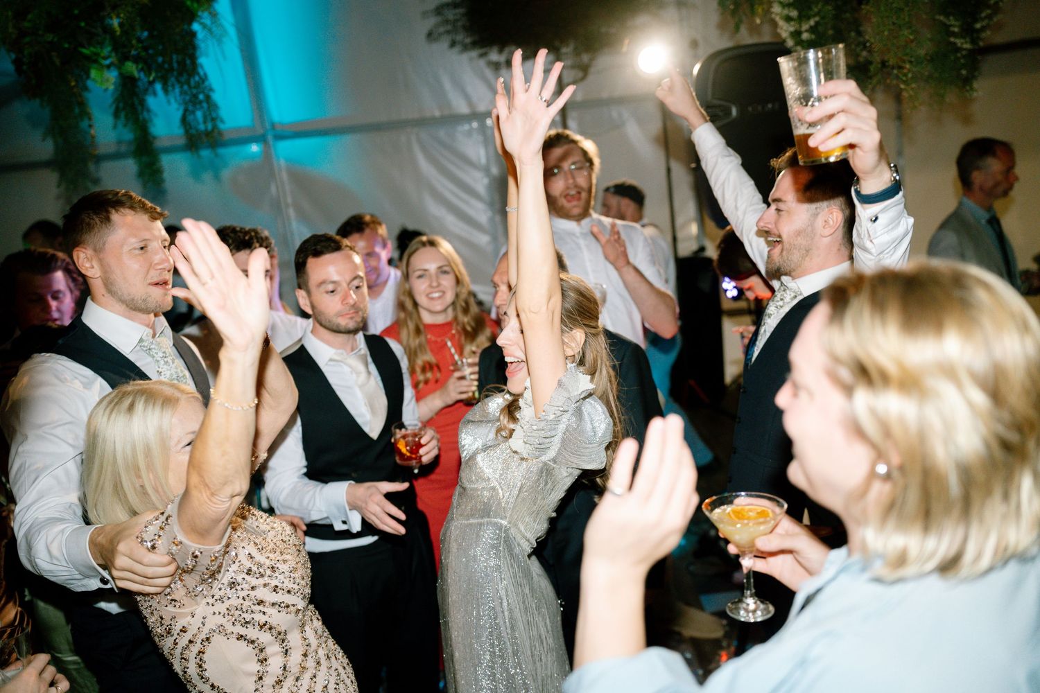 Wedding reception dance floor with blue lighting and guests celebrating.