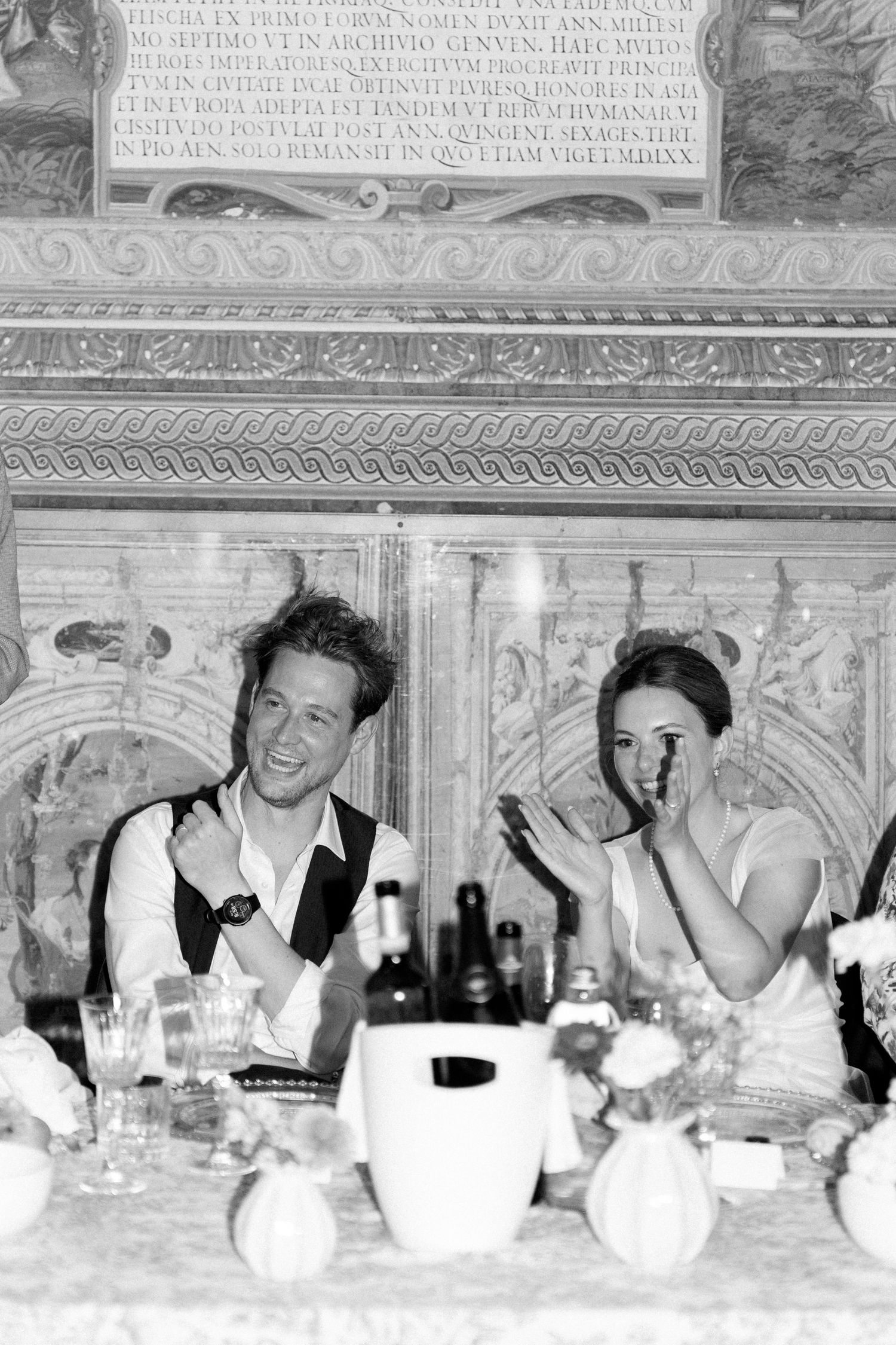 Vintage dinner party scene with ornate ceiling murals and elegant table settings.