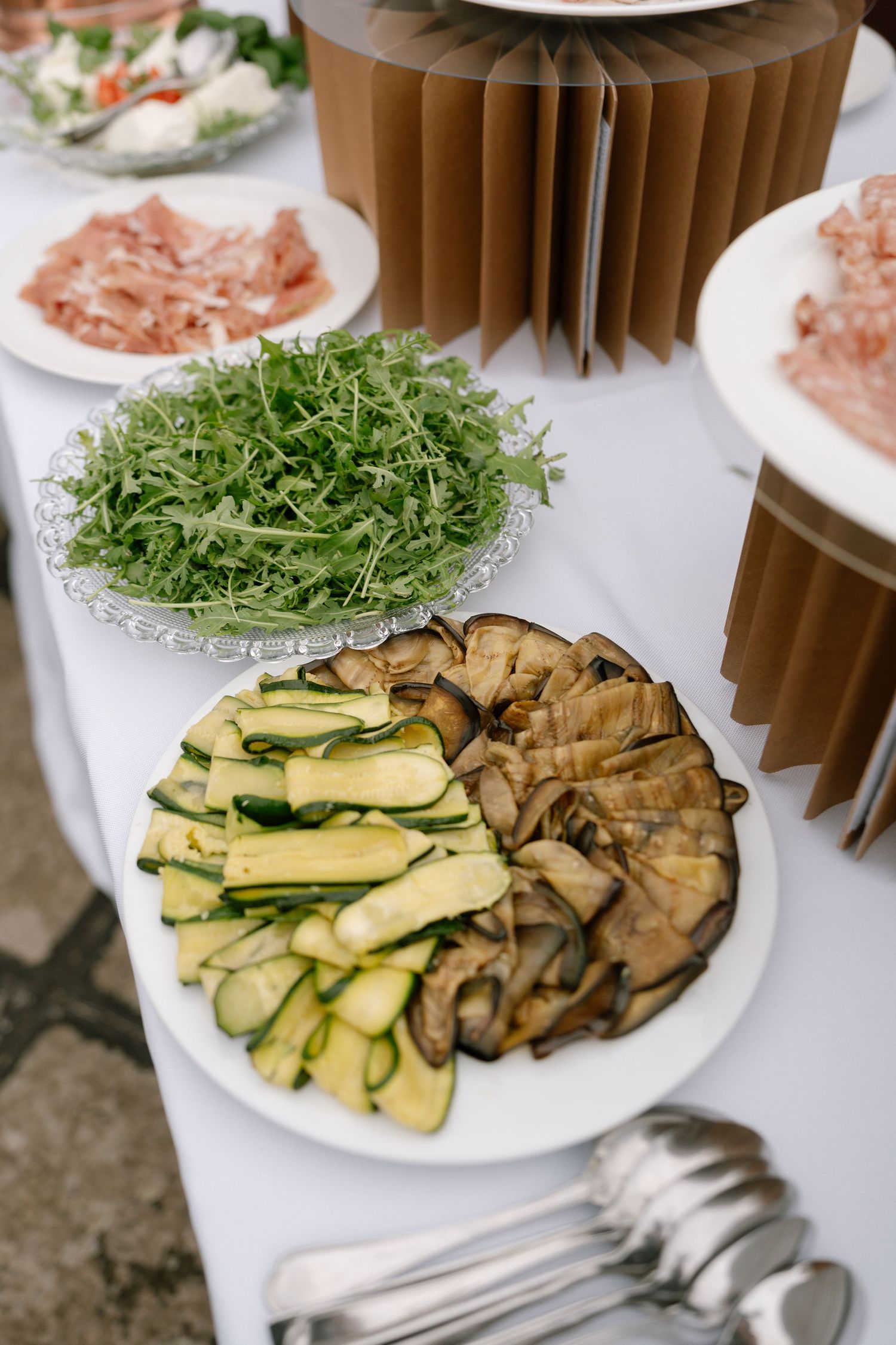 Fresh vegetable platter with zucchini, mushrooms and microgreens arranged on white plates.