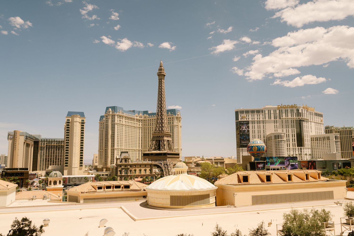 Las Vegas Strip skyline featuring Paris Hotel and Eiffel Tower replica under blue sky.