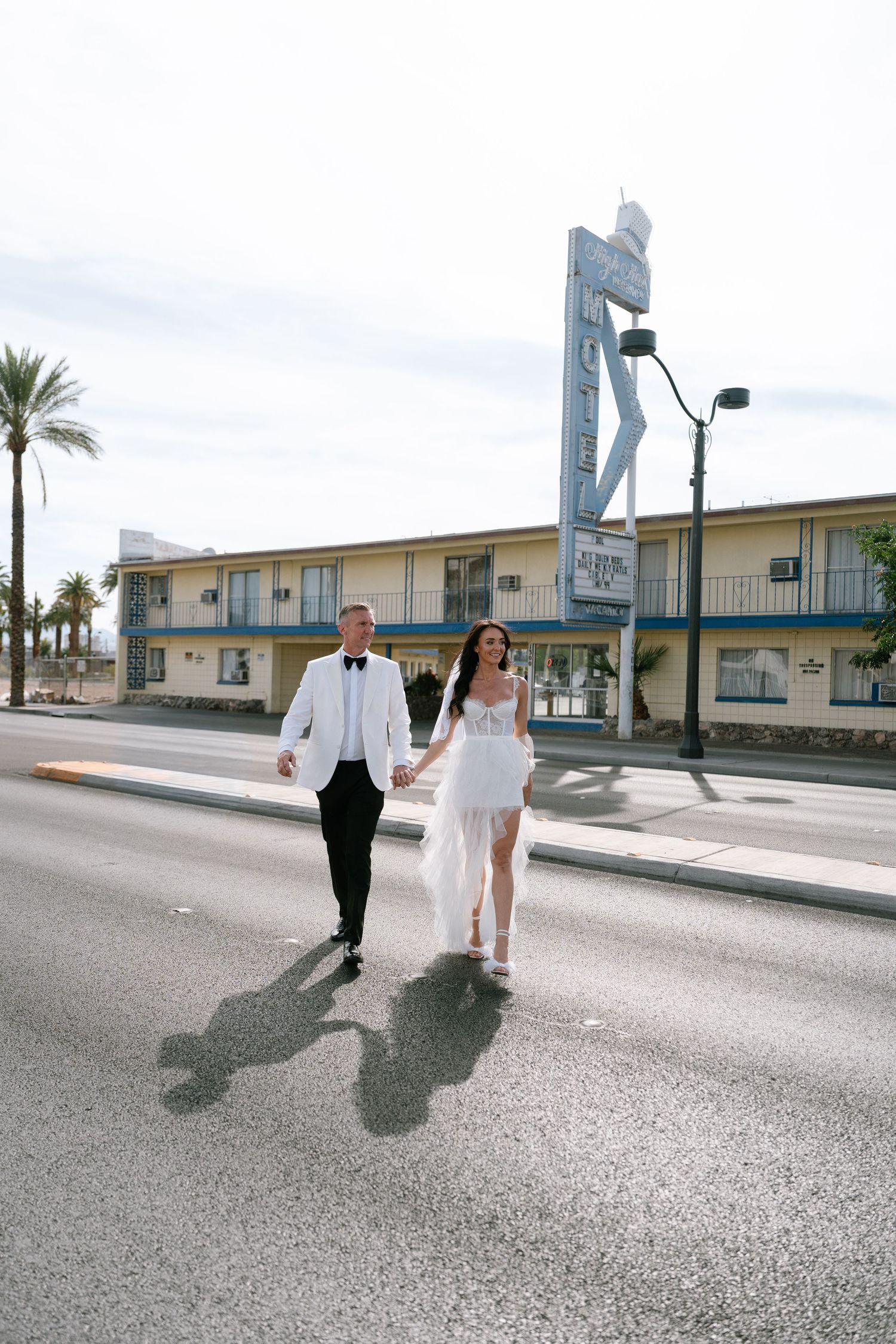 Newlyweds stroll down a palm-lined Las Vegas street after their chapel ceremony.