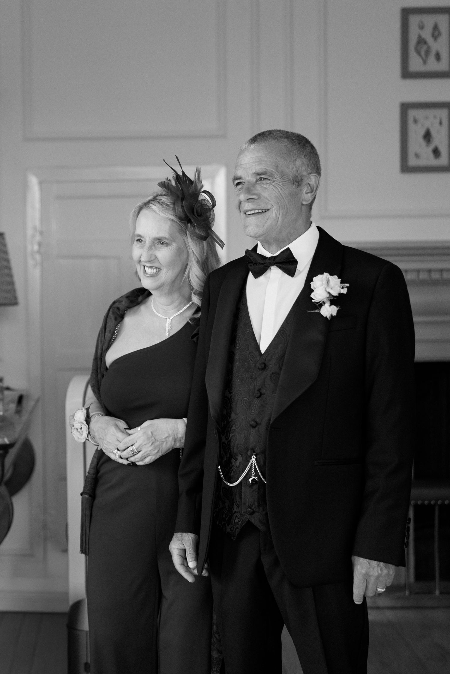 Black and white portrait of an elegant couple in formal wedding attire standing indoors.