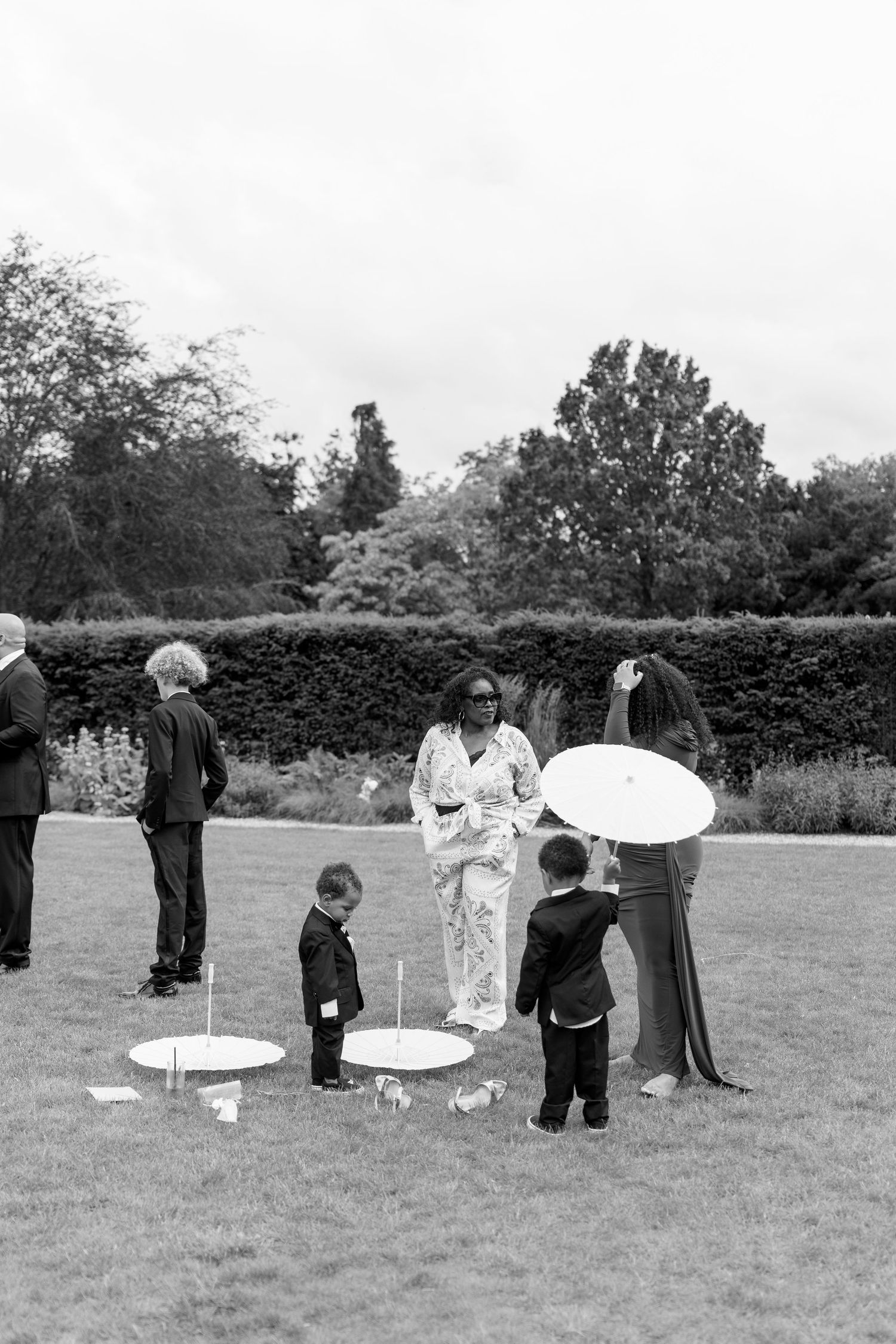 Black and white photo of wedding guests with children playing lawn games at an outdoor garden reception.