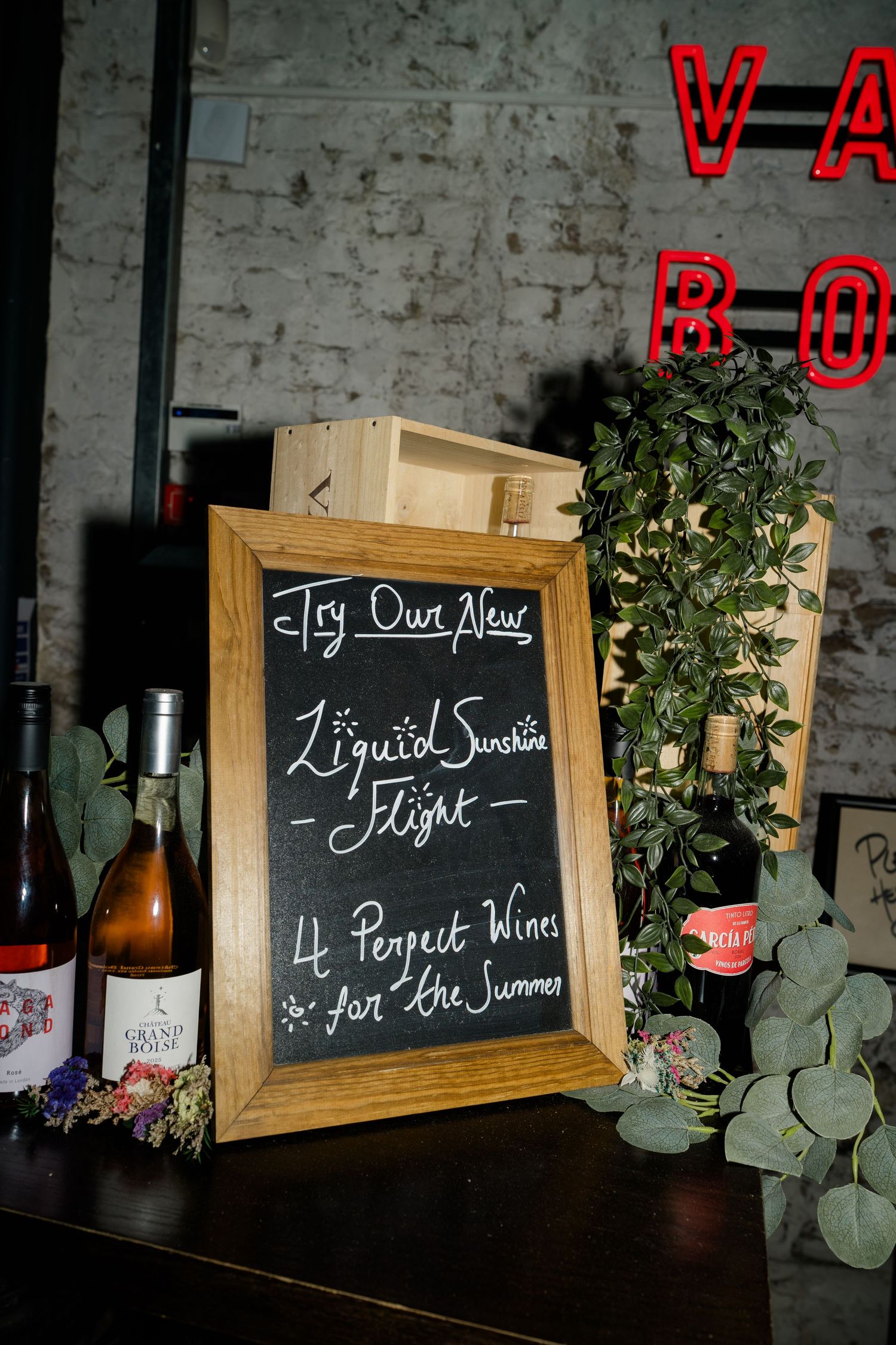 Chalkboard sign advertising Liquid Sunshine wine flight with four summer wines at Vagabond bar.