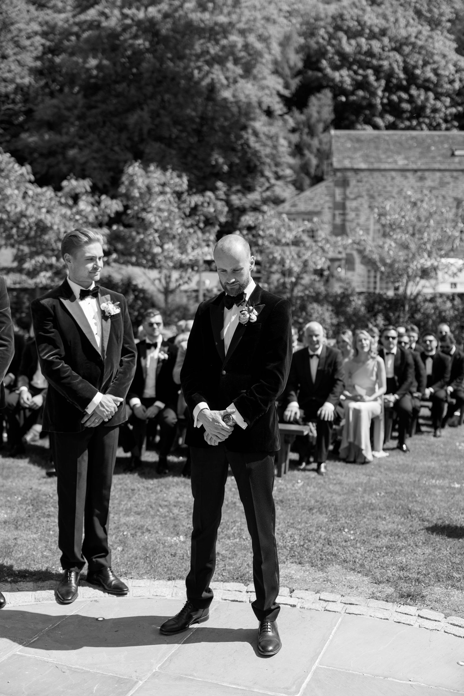 Black and white photo of groomsmen standing on marked positions at an outdoor ceremony.