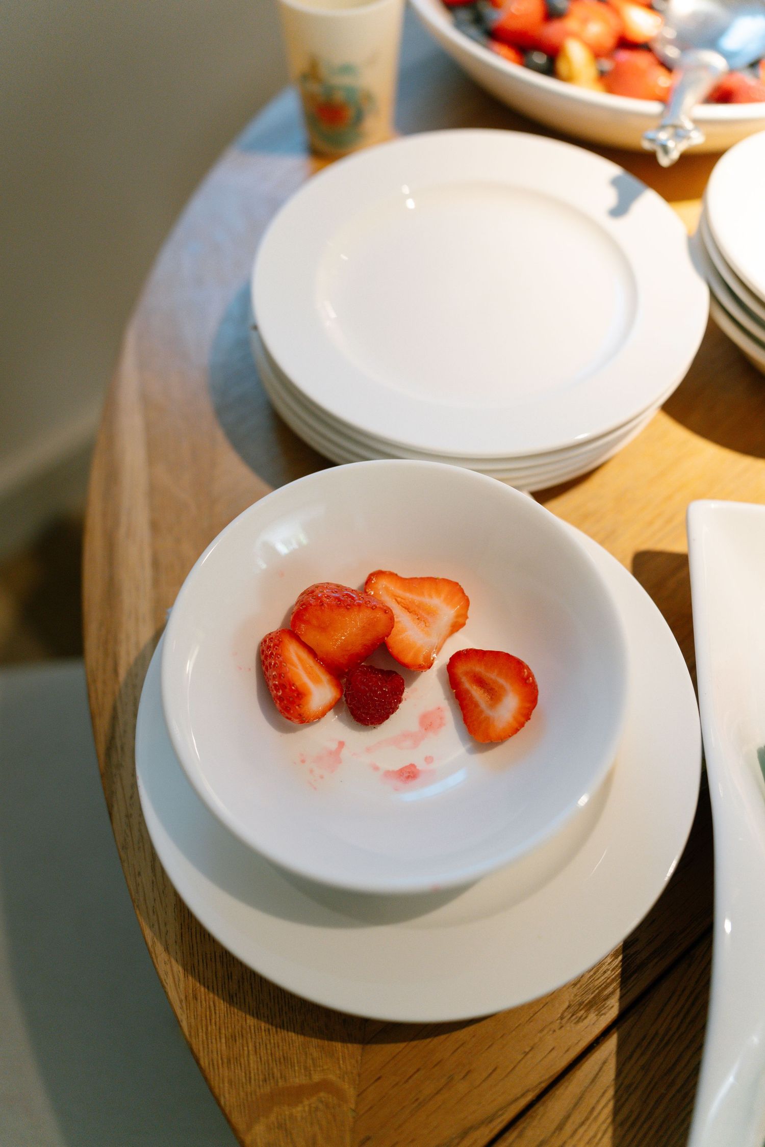 Fresh strawberries served on white plates arranged on a wooden surface.