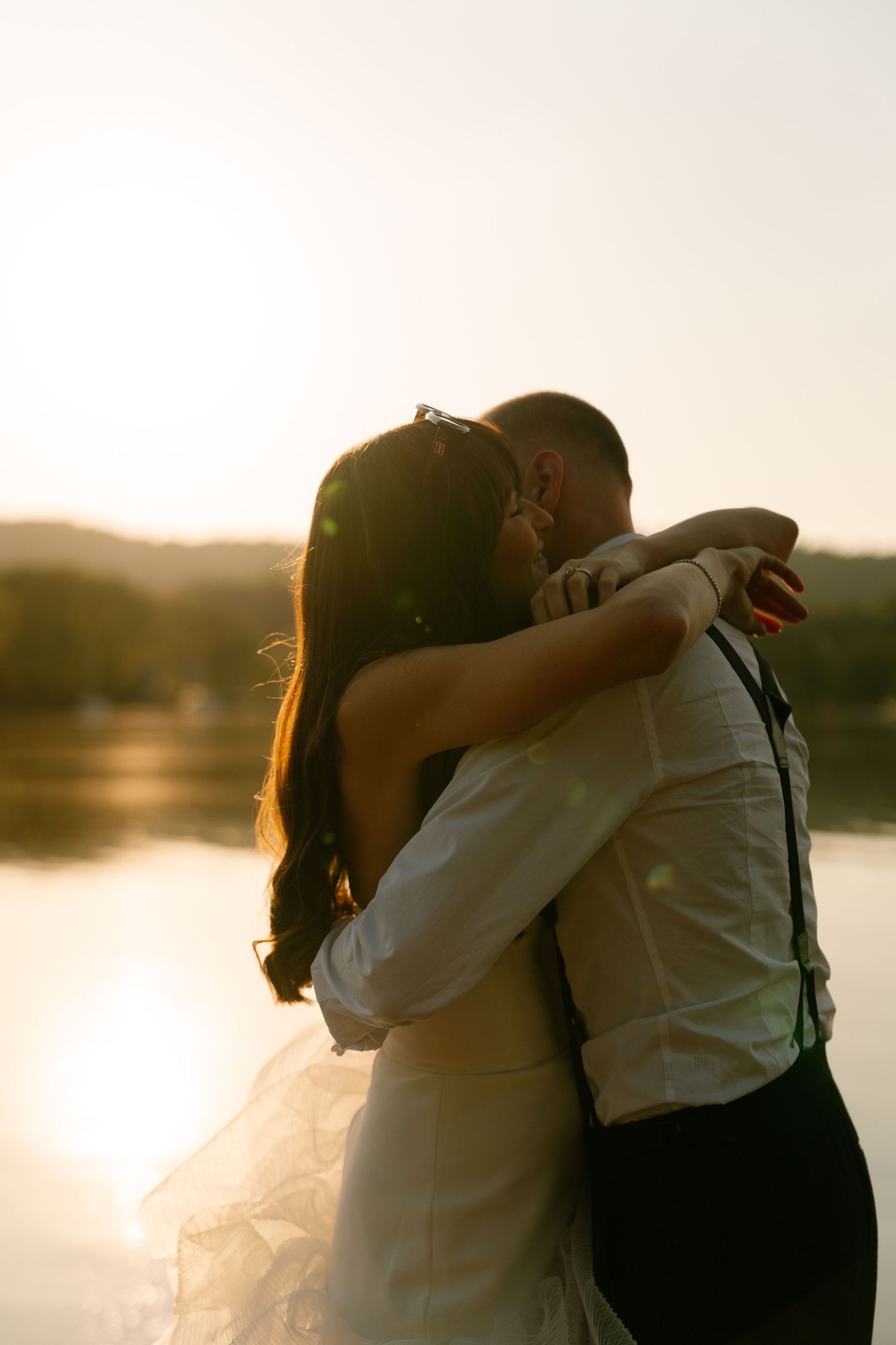 Silhouetted couple embracing at sunset by a peaceful lakeside.