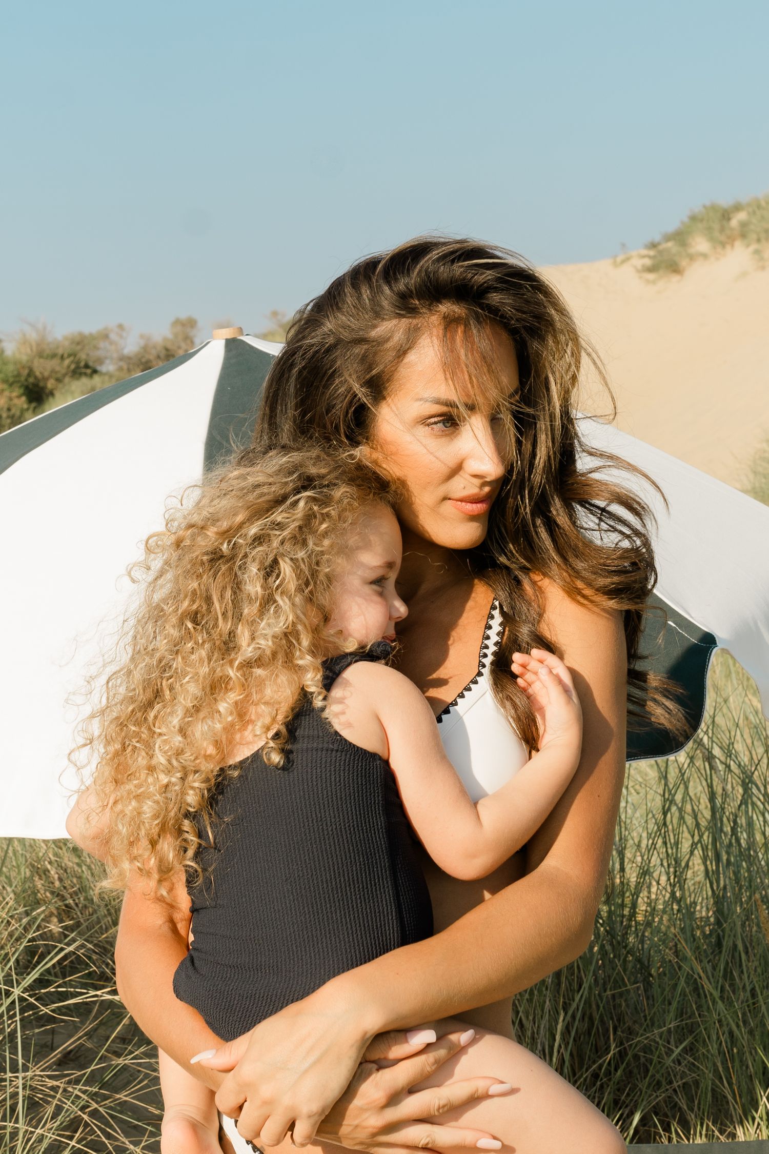 An intimate beach portrait captured against sand dunes and beach grass on a sunny day.