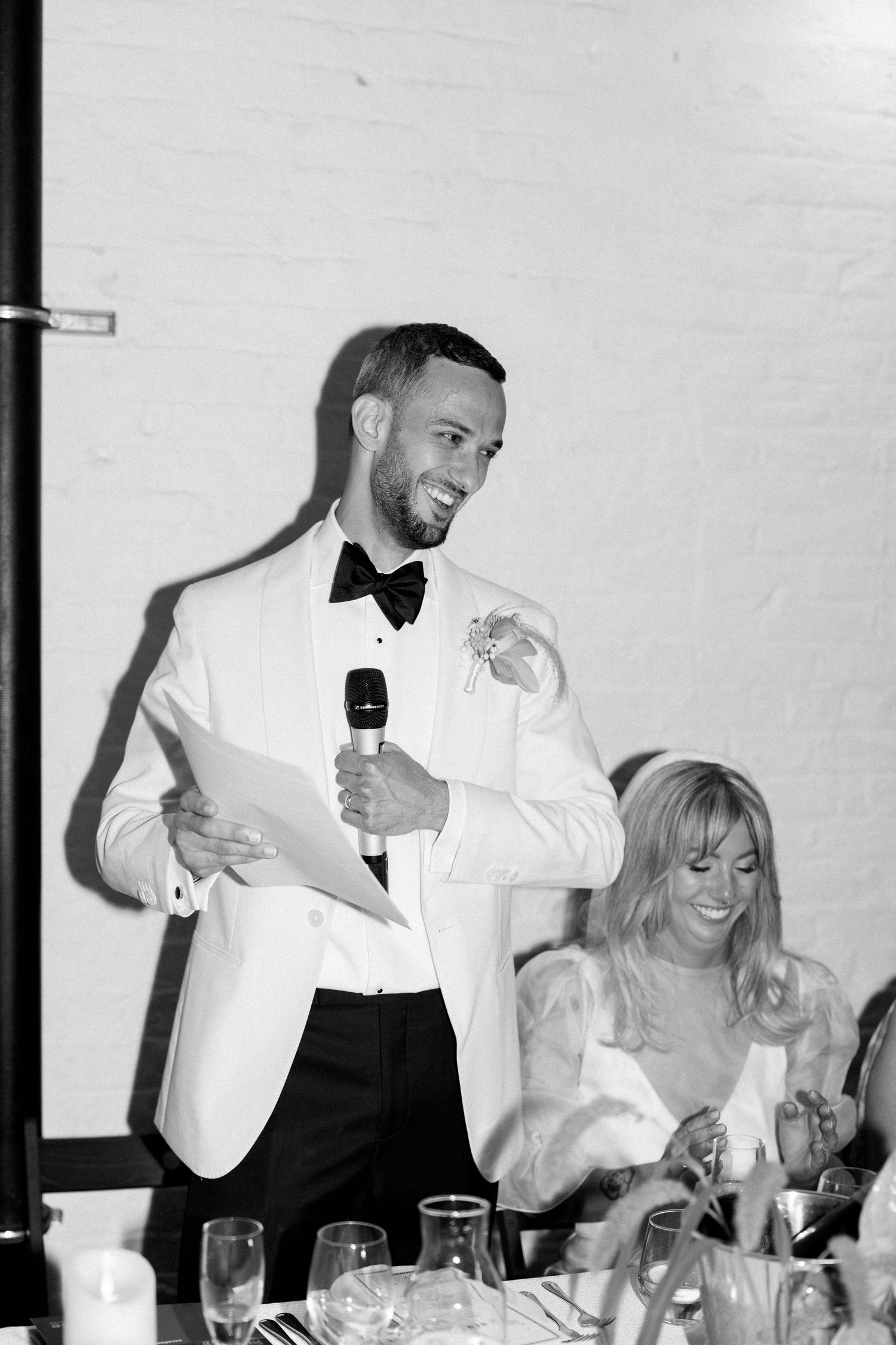 Wedding celebration with guests in formal attire giving toasts at an elegant dinner table.
