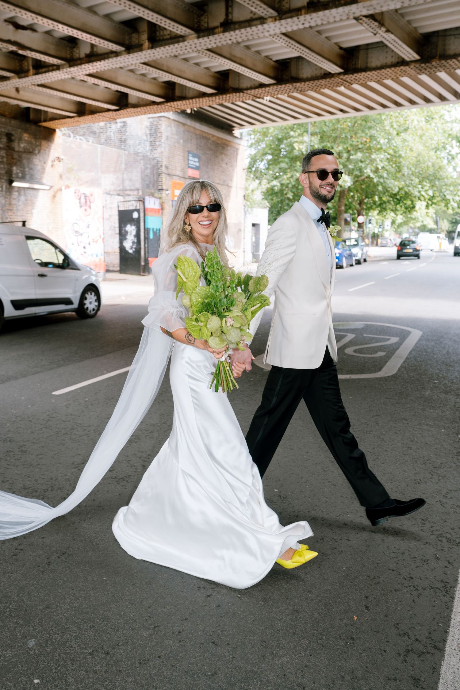 Candid wedding moments captured under a concrete overpass.