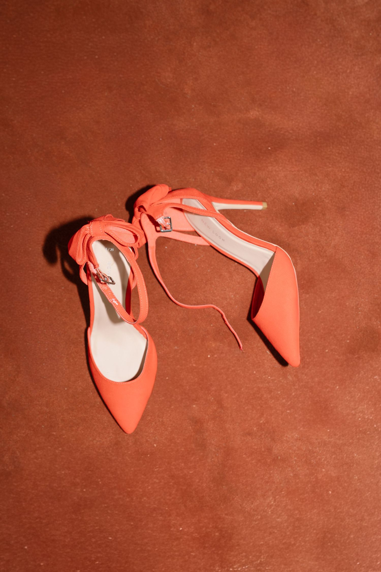 A sequence of six photos showing a coral high heel shoe falling over on a brown velvet surface.