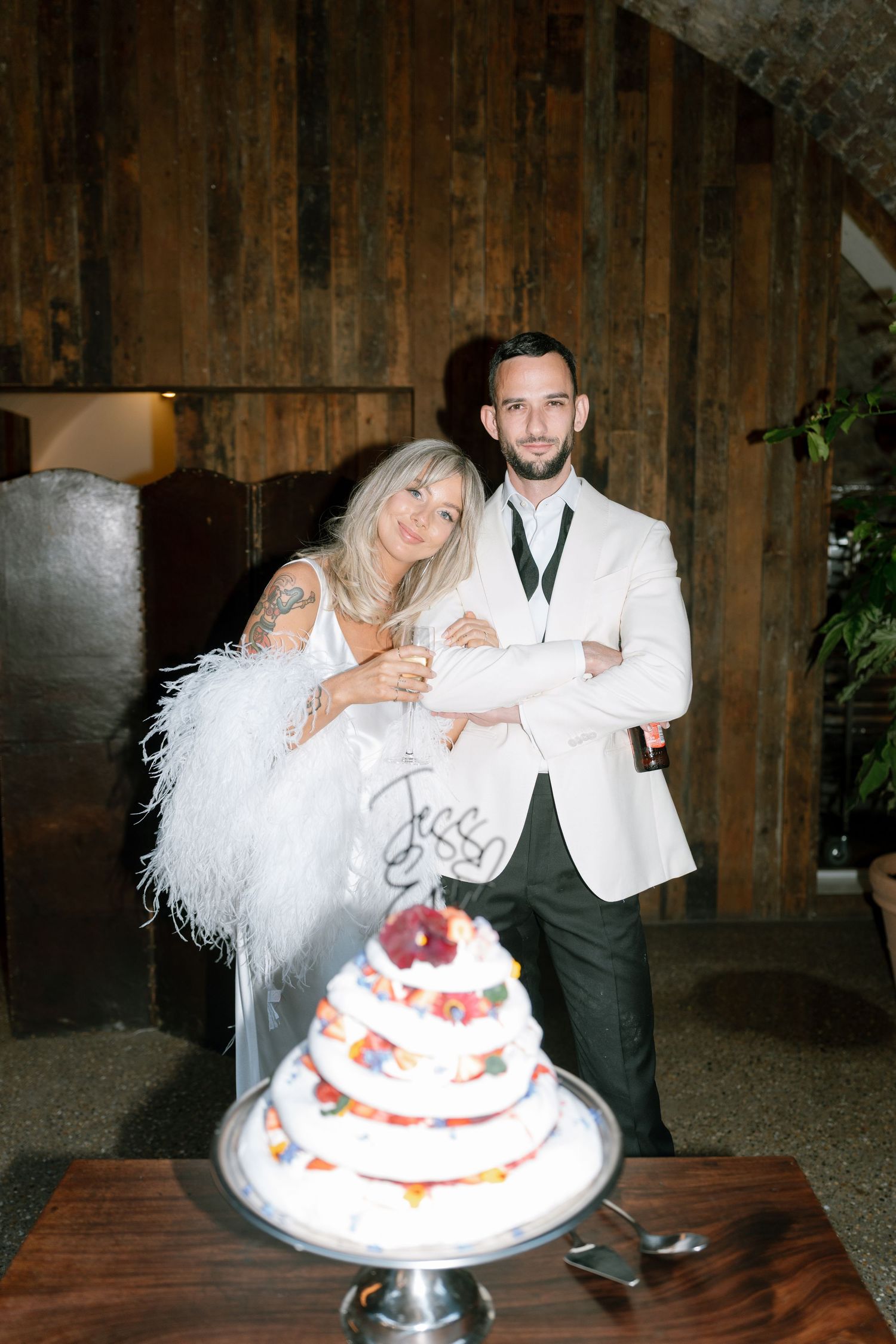 Newlyweds cutting their white wedding cake decorated with flowers.