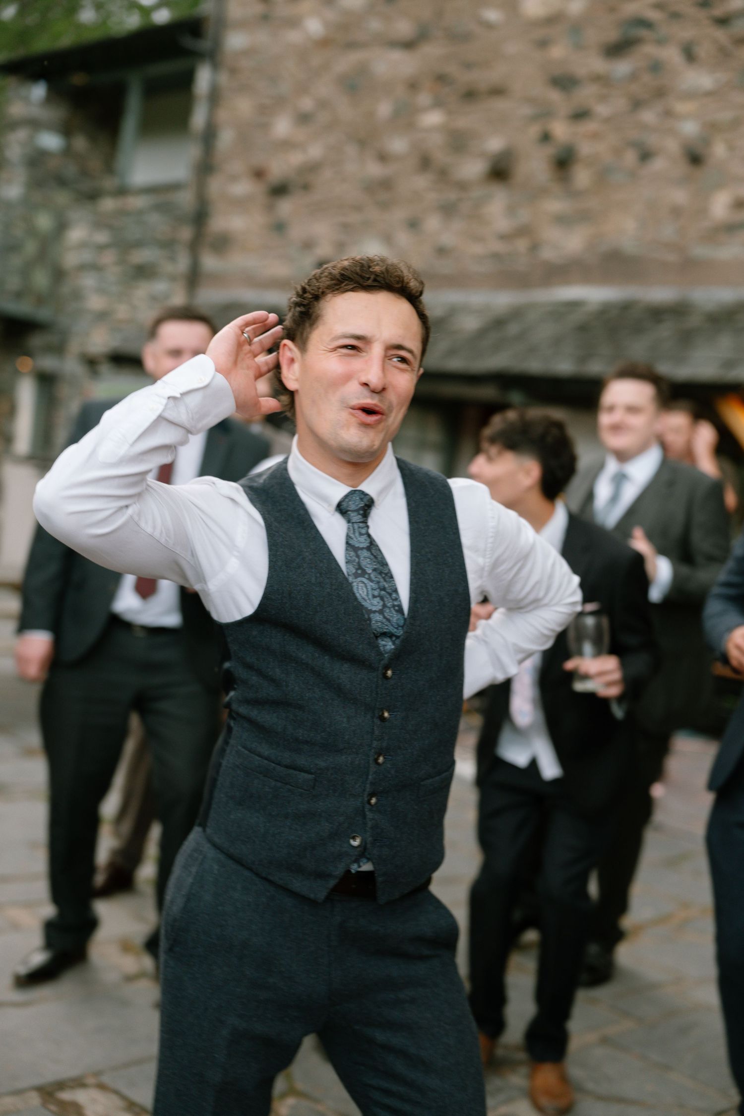 Wedding guests in formal attire dancing and celebrating outdoors.