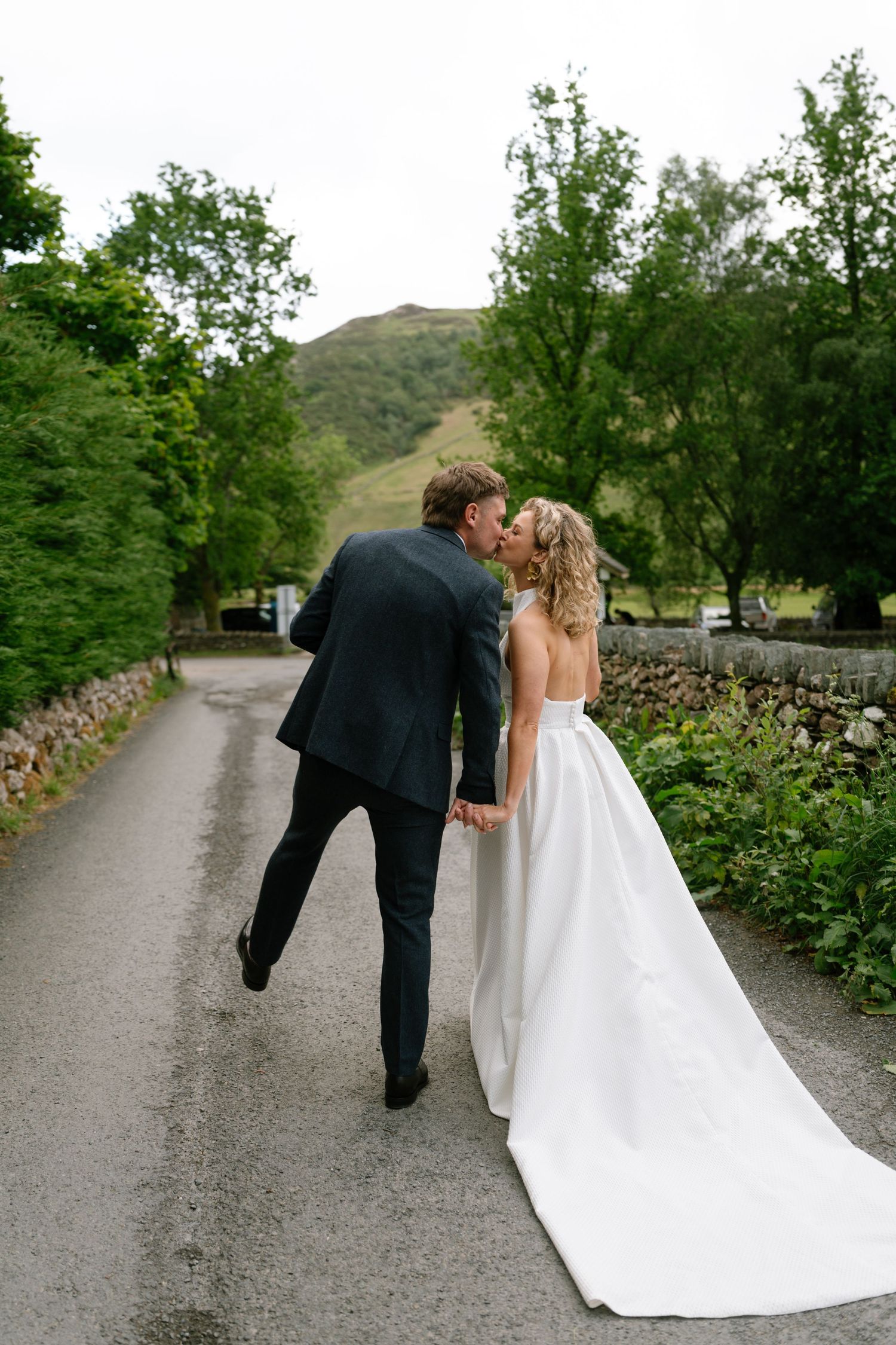 Sequence of newlyweds walking down a countryside path with mountains in background.