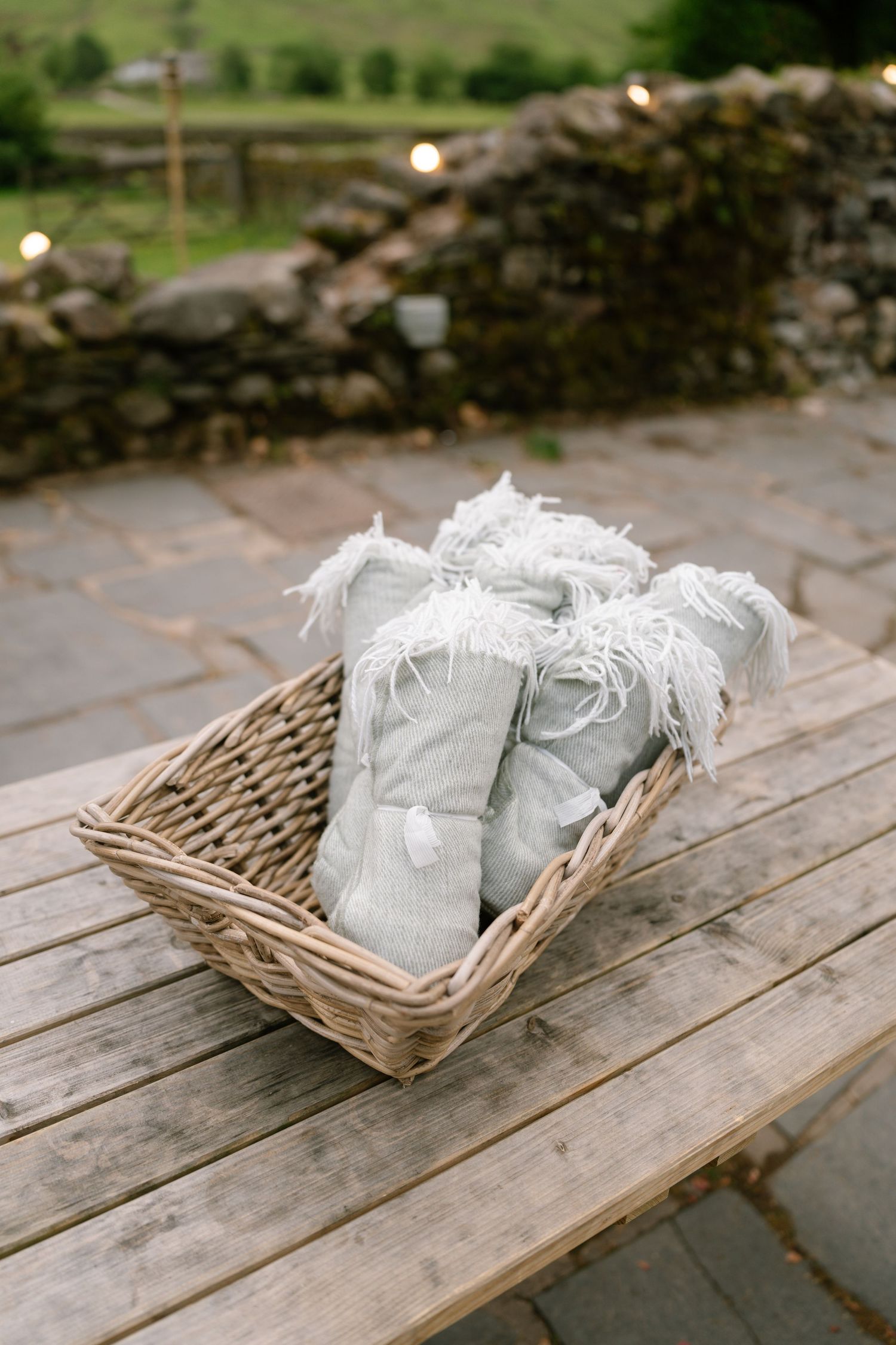 Small woven baskets with white sachets displayed on rustic wooden table.