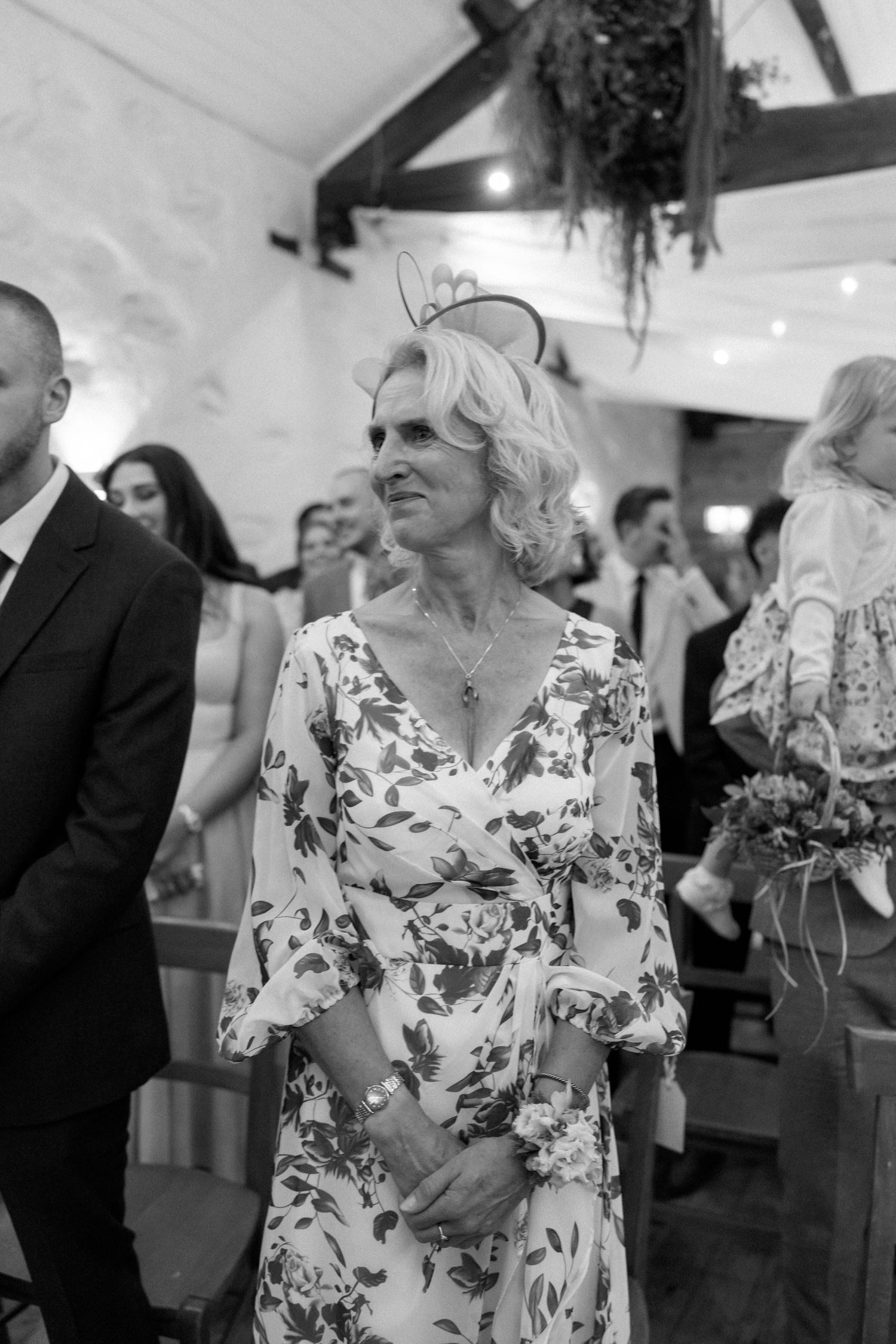 Wedding reception guests dancing and celebrating in a rustic indoor venue with floral decor.