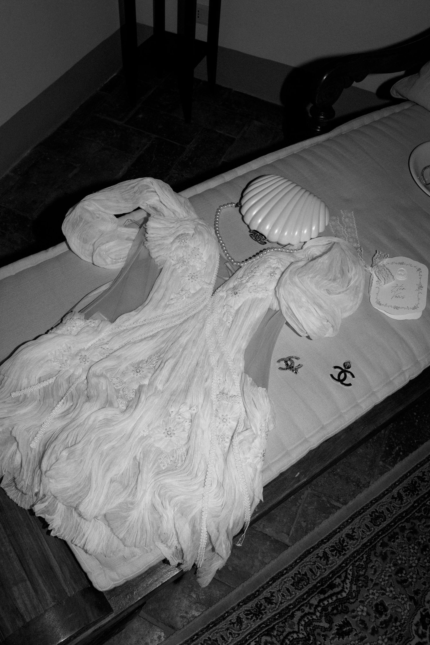 A white wedding dress laid out on display in dramatic black and white lighting.