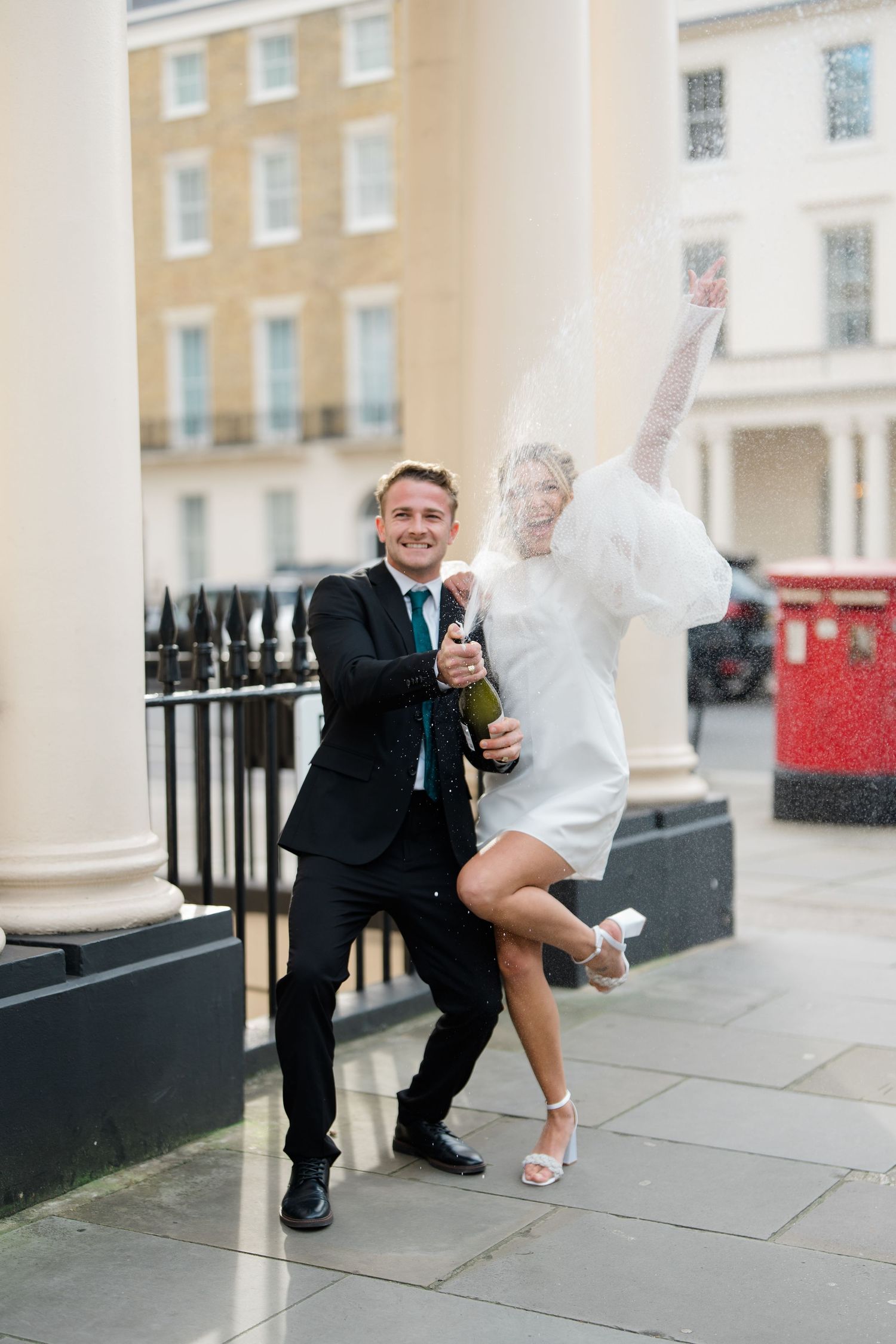 A couple performing a playful dance move on a city sidewalk.