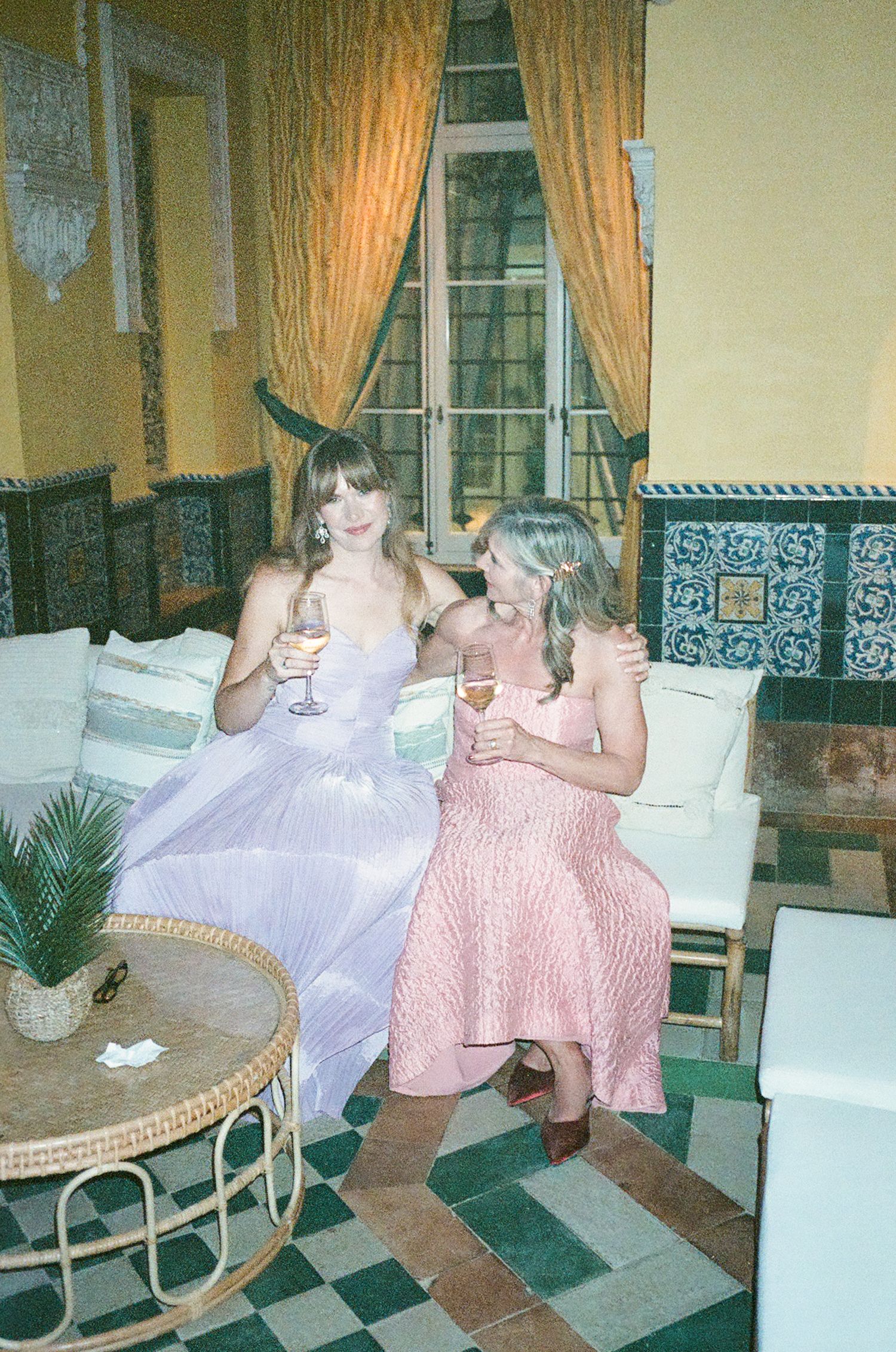 Vintage photo showing people lounging on wicker chairs in a room with checkered floors and peach curtains.