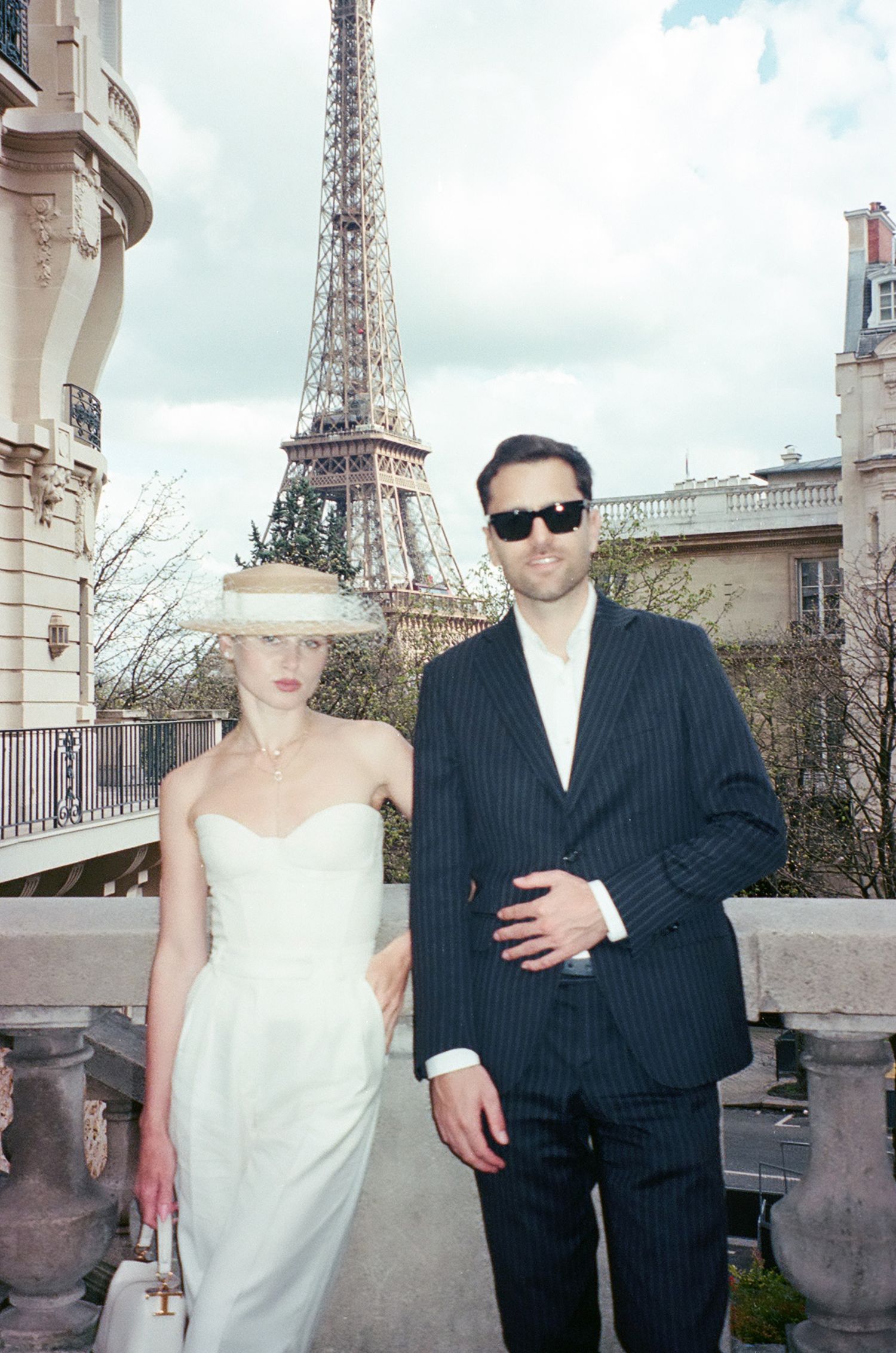 A couple poses for wedding photos in front of the Eiffel Tower in Paris with the iconic landmark visible in the background.