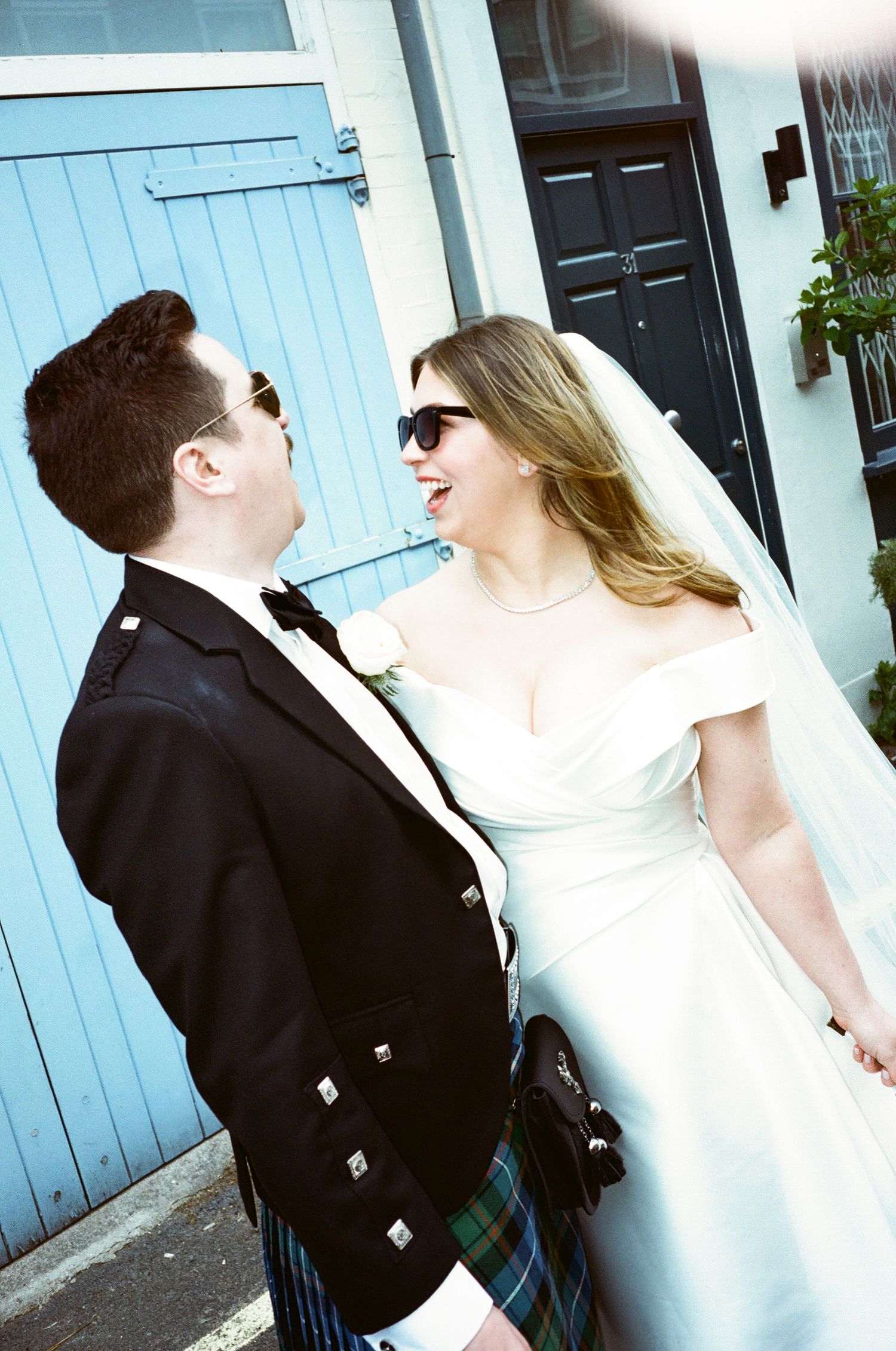 A couple in wedding attire share a tender moment against a blue door backdrop in a series of candid shots.