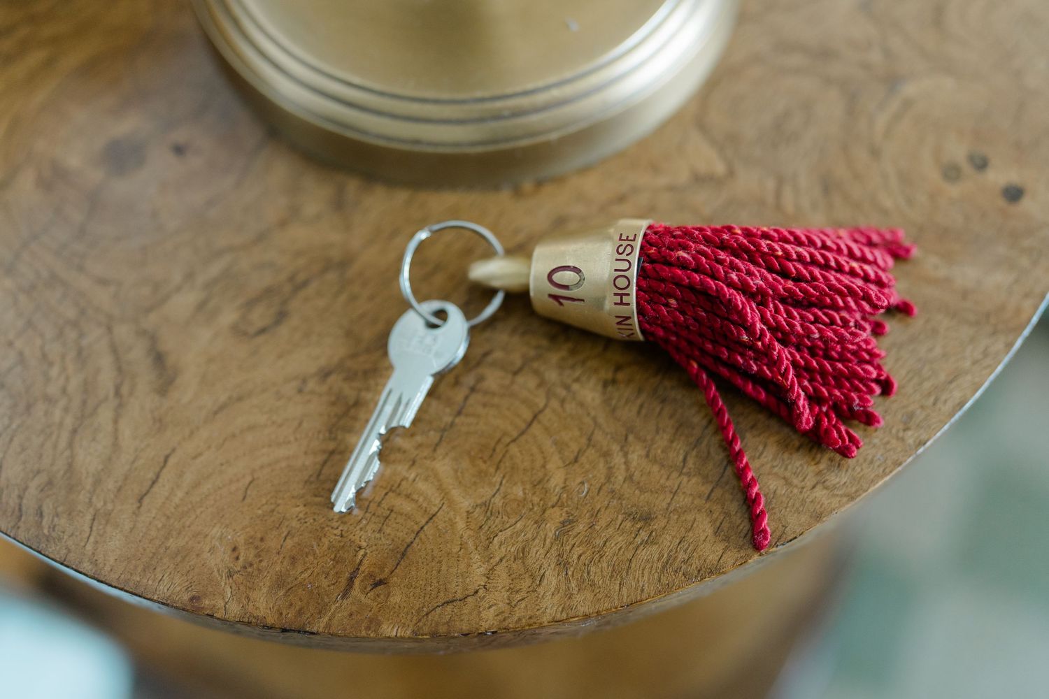 A vintage hotel room key with a red tassel keychain resting on a wooden table.