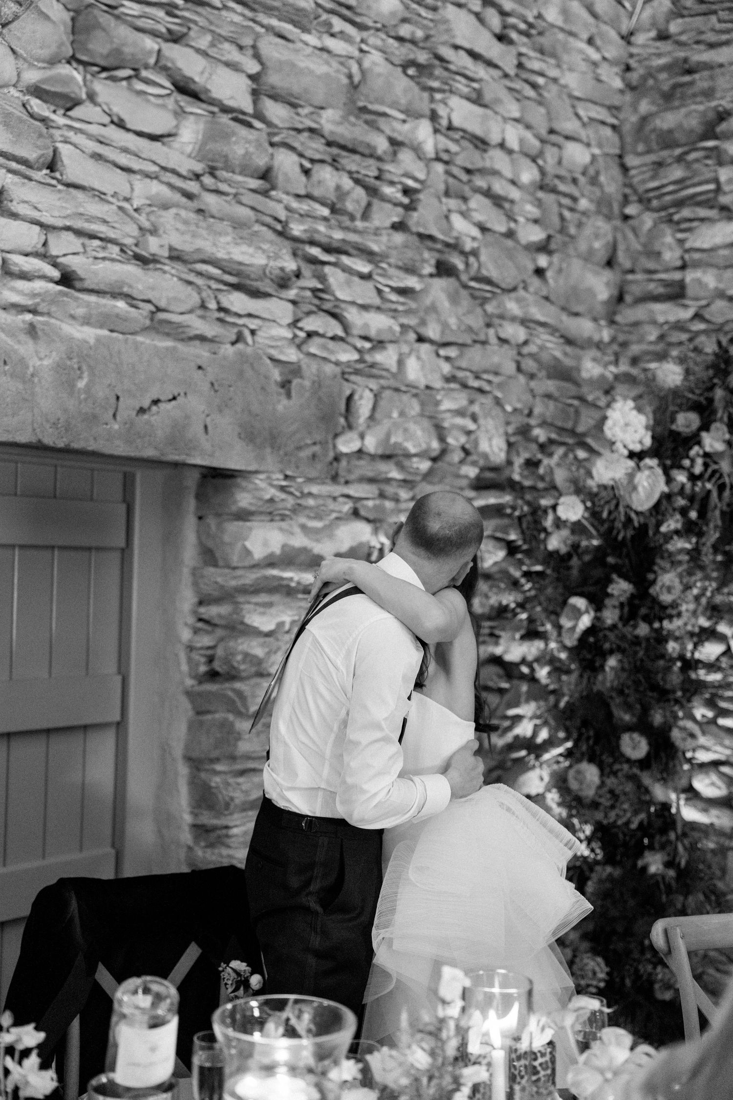 Wedding celebration in a historic stone building with elegant table settings and floral arrangements.