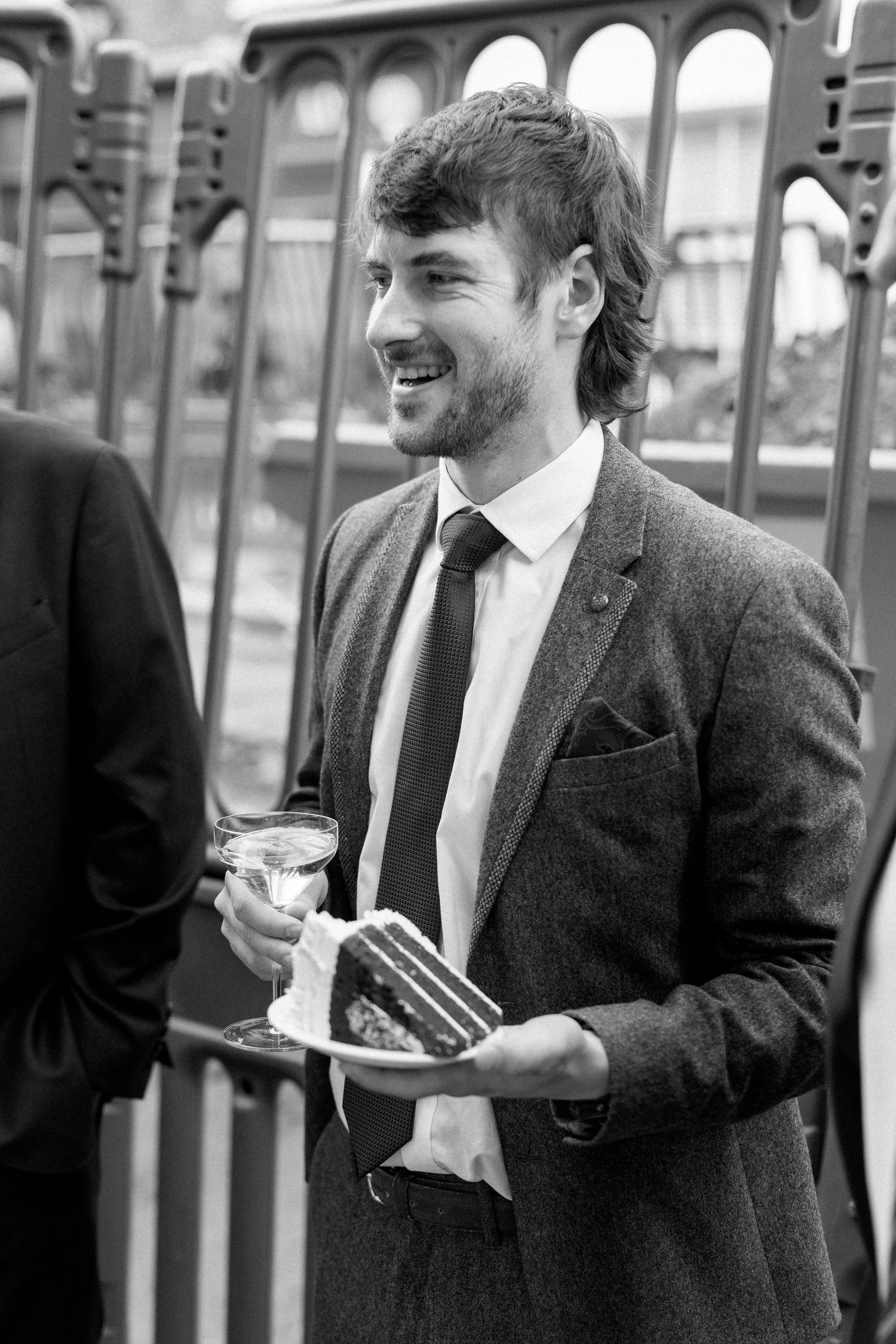 Wedding guests in formal attire enjoying food and drinks at an outdoor reception.