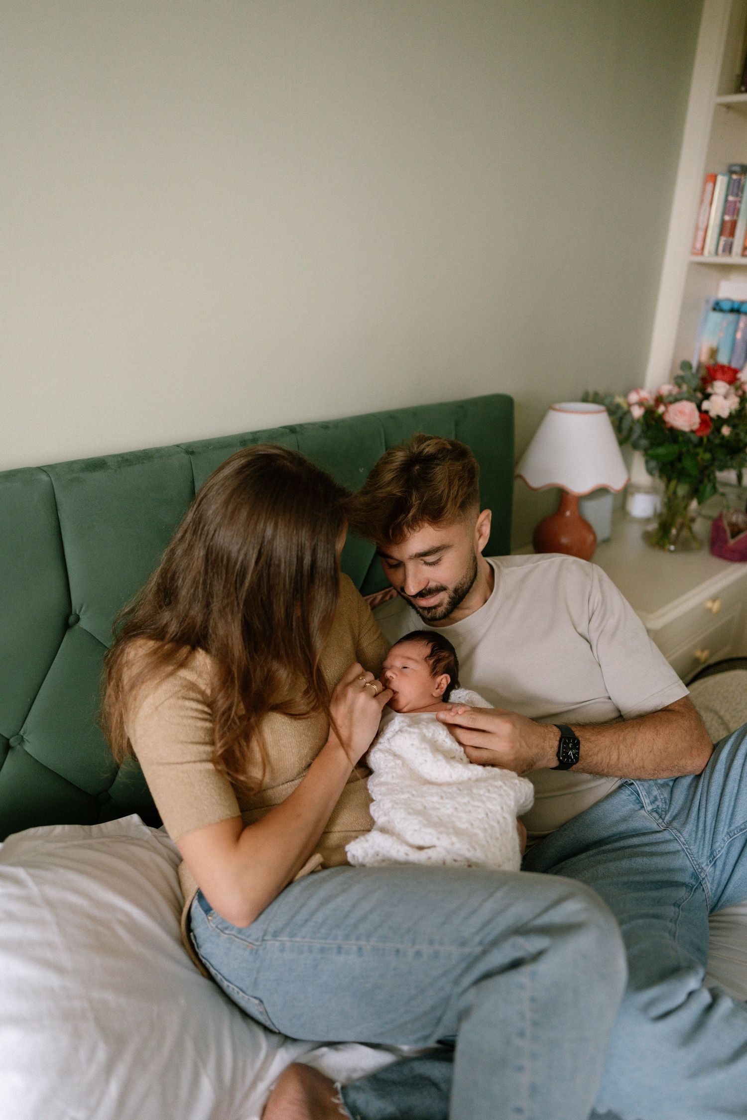 Family relaxing together on green couch while bonding with newborn.
