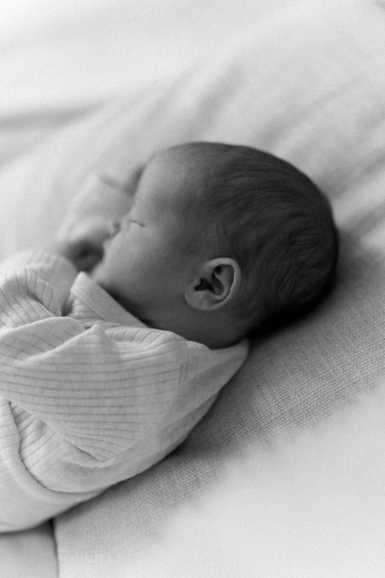 Close-up series of a newborn baby sleeping peacefully in soft white swaddling.