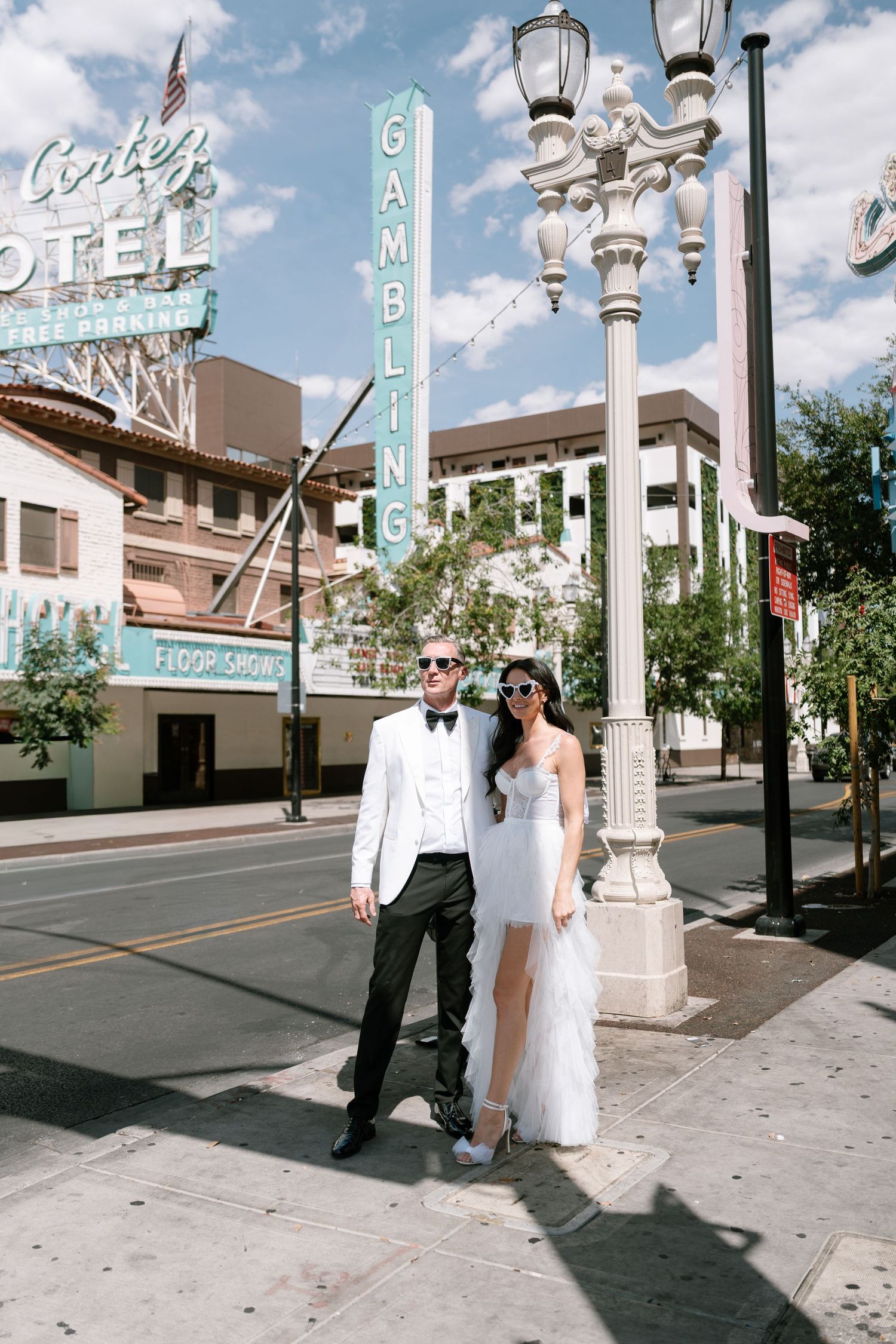 Newlyweds pose in front of classic Gambling neon sign and vintage street lamps.