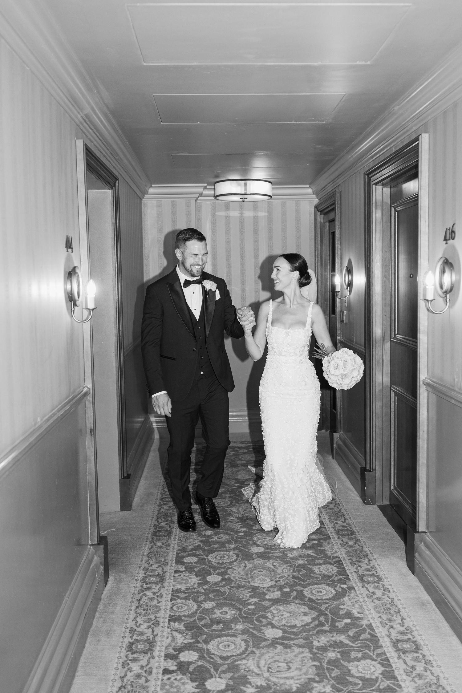 Black and white photos of newlyweds walking down elegant hotel hallway.
