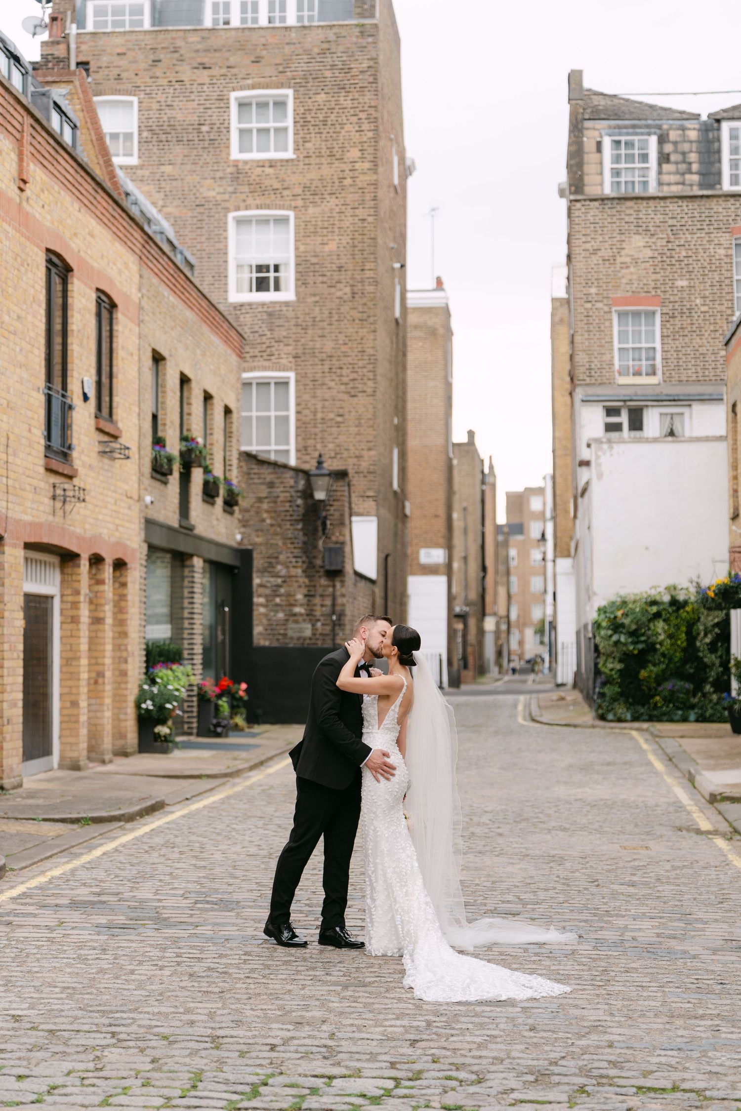 Romantic wedding photos captured on a charming cobblestone street with brick architecture.