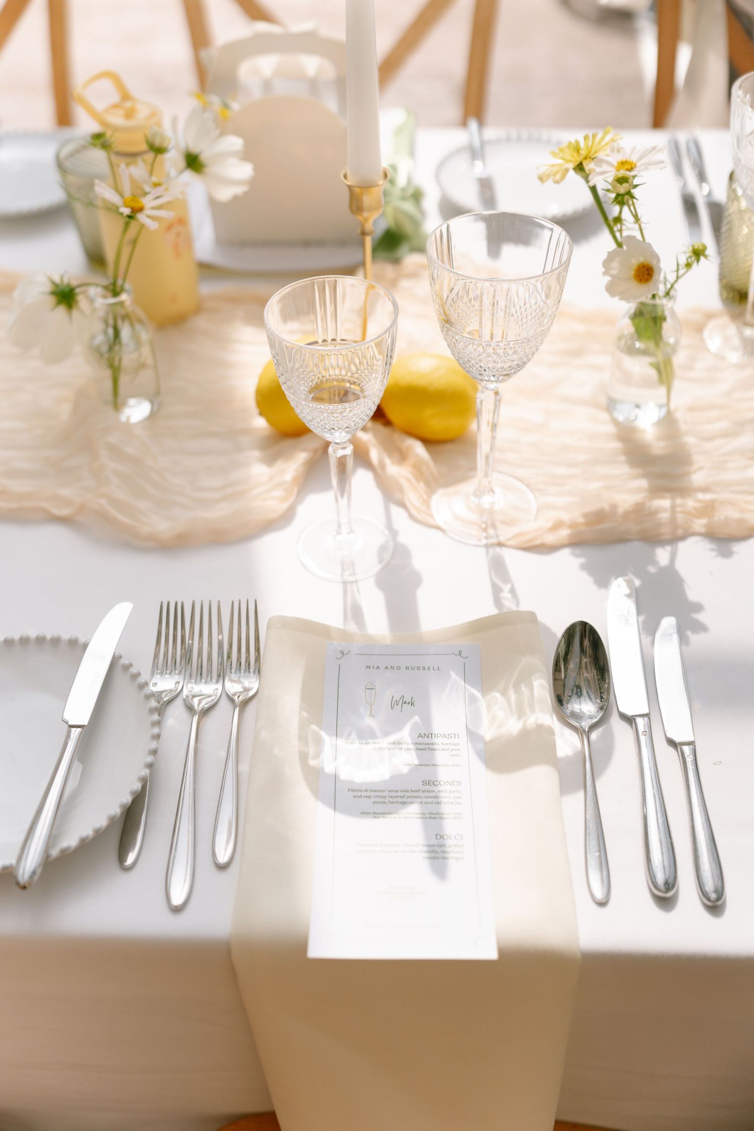 Elegant table settings with crystal glassware, silver cutlery, and yellow citrus accents.