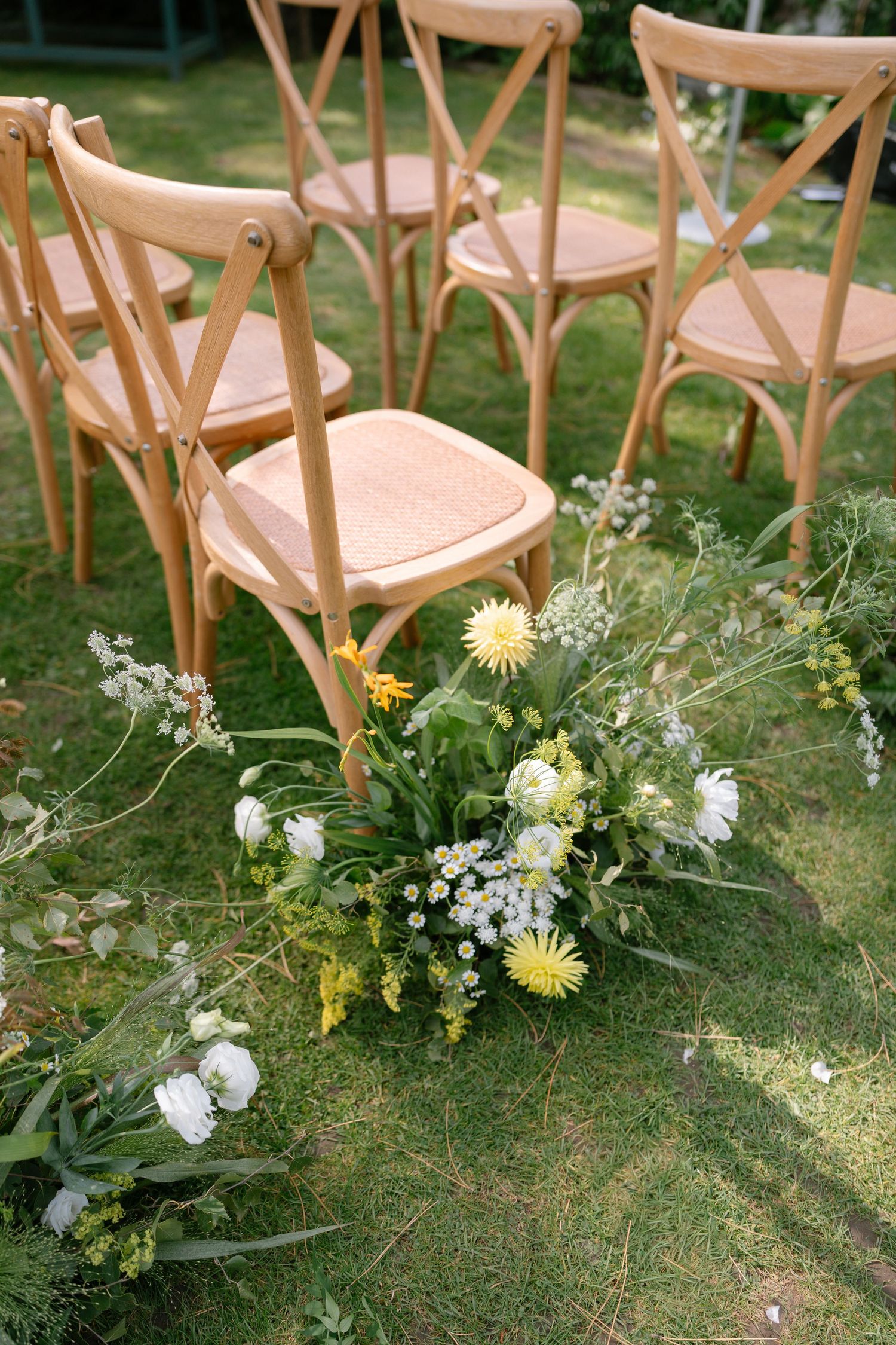 Garden ceremony seating with natural floral arrangements lining the aisle.