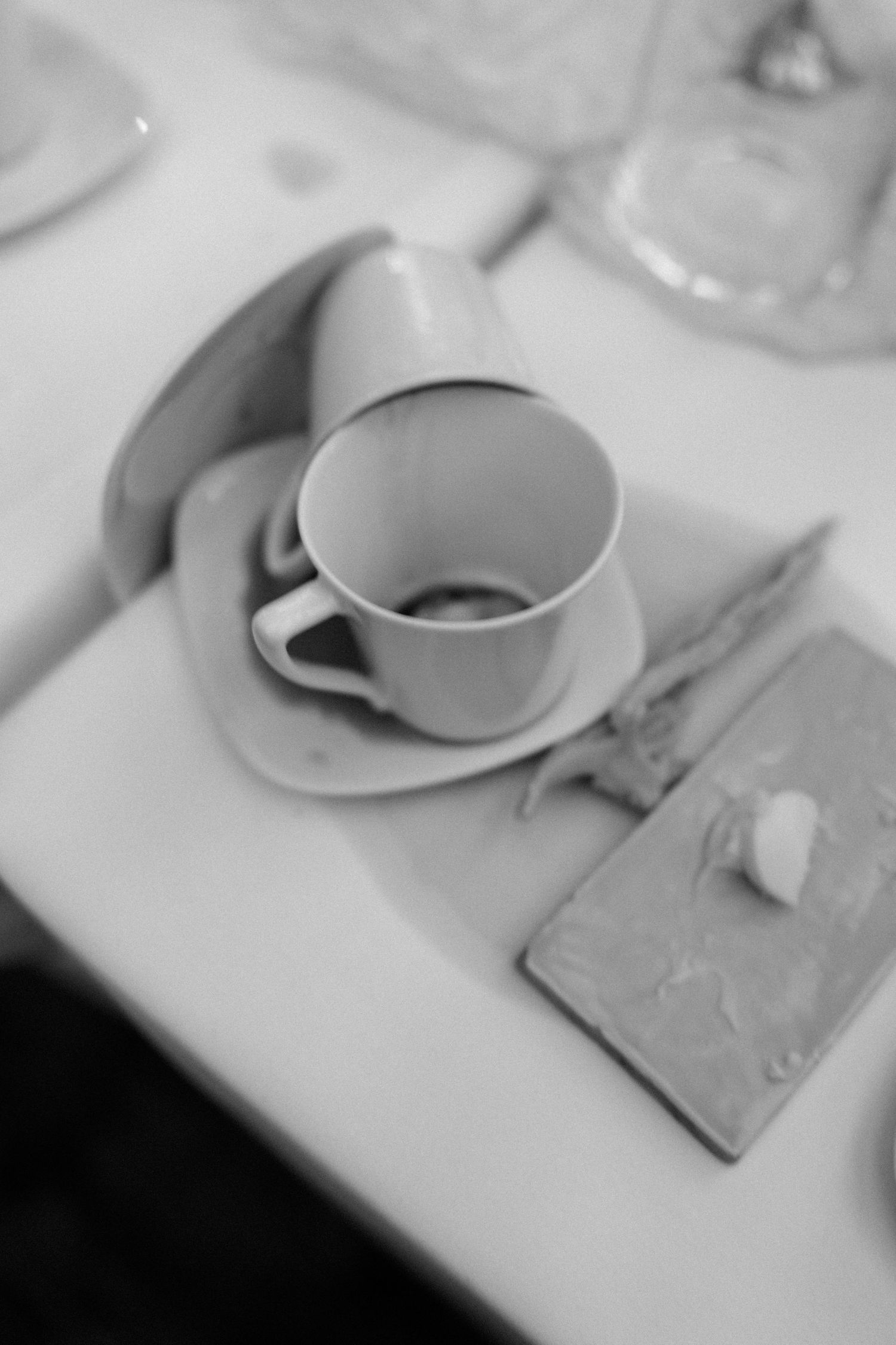 Coffee cups and saucers arranged on a white tablecloth in an elegant table setting.