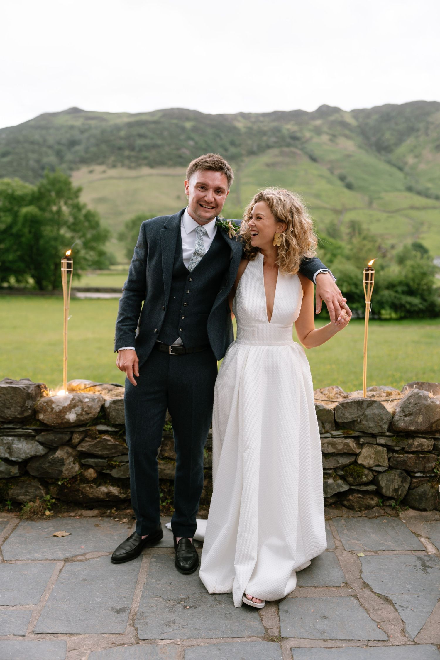 Couple shares intimate moments on stone patio during wedding celebration with mountain backdrop.