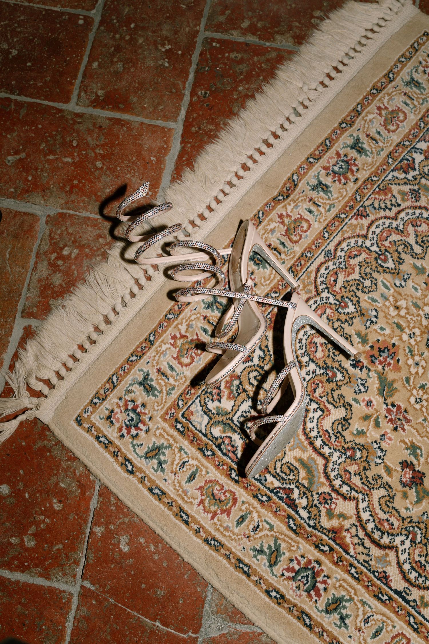 Close-up detail of an ornate patterned rug corner on terracotta tiles.
